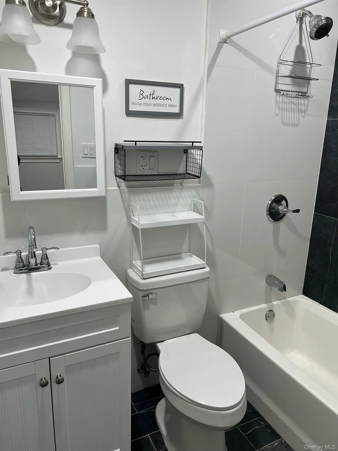 Bathroom featuring bathtub / shower combination, vanity, and dark tile patterned floors Bathroom featuring bathtub / shower combination, vanity, and dark tile patterned floors