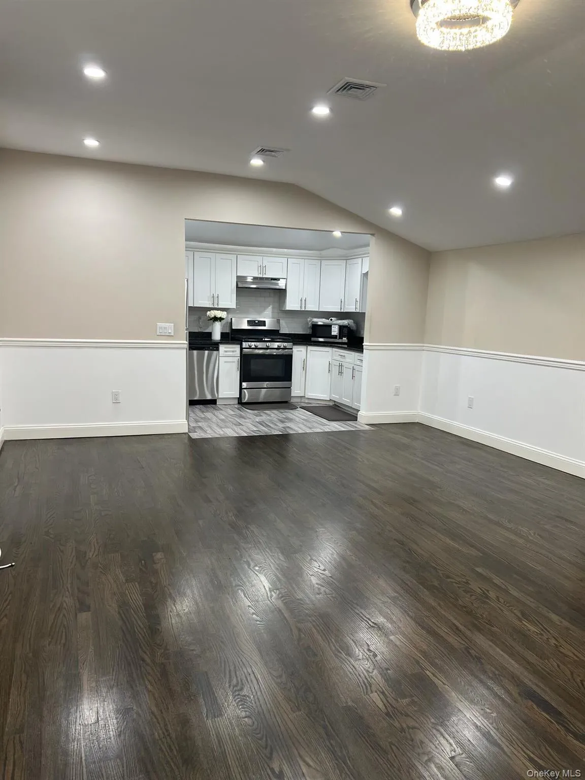 Kitchen featuring white cabinetry, appliances with stainless steel finishes, dark countertops, recessed lighting, and under cabinet range hood Kitchen featuring white cabinetry, appliances with stainless steel finishes, dark countertops, recessed lighting, and under cabinet range hood