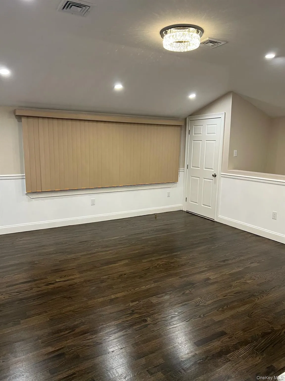 Empty room featuring vaulted ceiling, recessed lighting, and dark wood-type flooring Empty room featuring vaulted ceiling, recessed lighting, and dark wood-type flooring