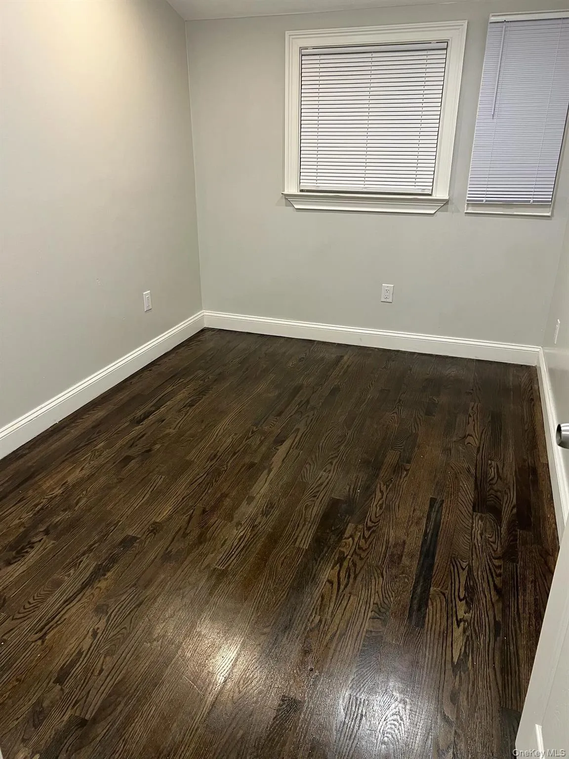 Empty room with dark wood finished floors and baseboards Empty room with dark wood finished floors and baseboards