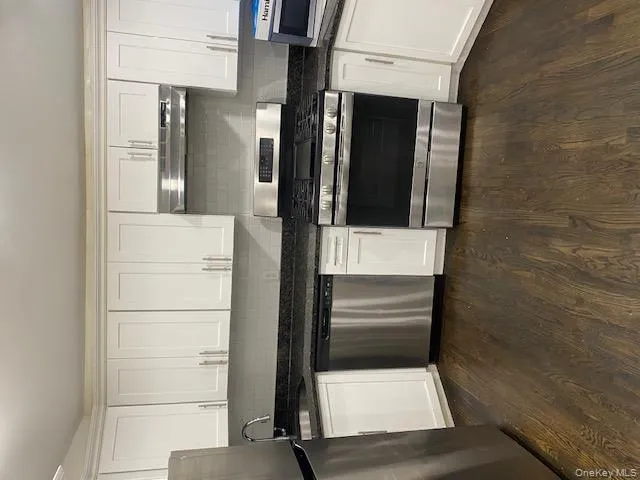 Kitchen featuring stainless steel range, dishwashing machine, fridge, tasteful backsplash, and white cabinetry Kitchen featuring stainless steel range, dishwashing machine, fridge, tasteful backsplash, and white cabinetry