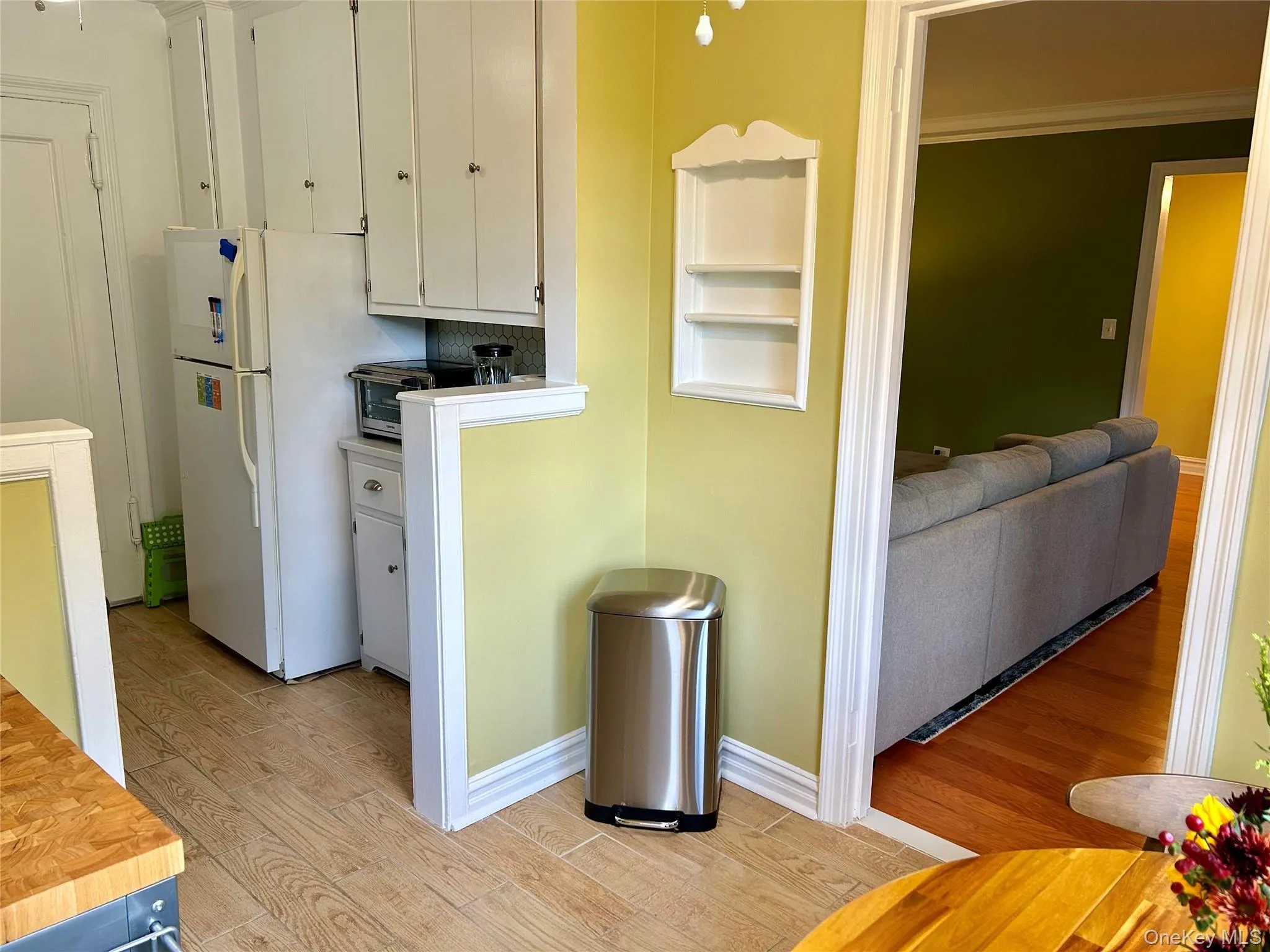 Kitchen with light tile flooring, freestanding refrigerator, white cabinets, and ornamental molding Kitchen with light tile flooring, freestanding refrigerator, white cabinets, and ornamental molding