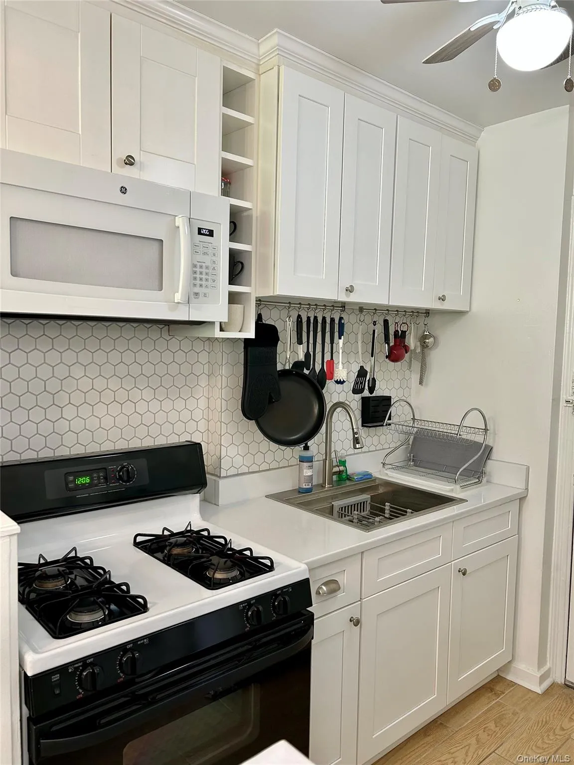 Kitchen featuring gas range, white microwave, and white cabinetry Kitchen featuring gas range, white microwave, and white cabinetry