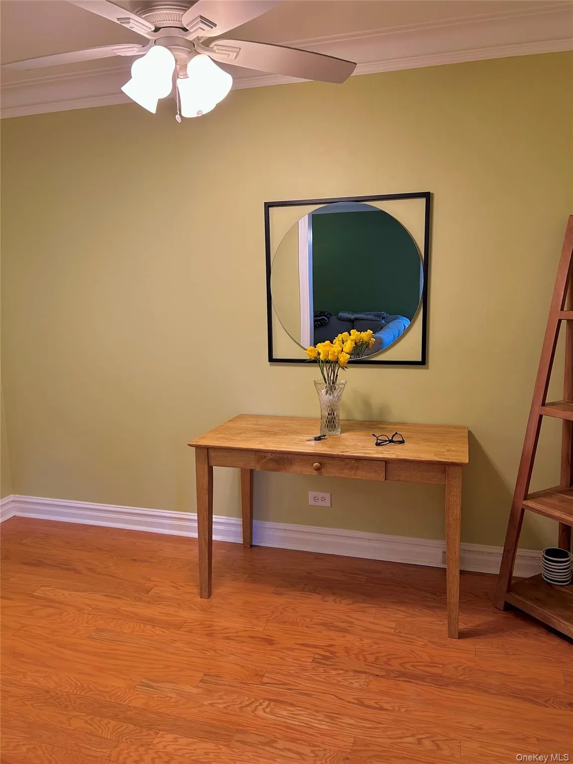 Detailed view of crown molding, wood finished floors, and a ceiling fan Detailed view of crown molding, wood finished floors, and a ceiling fan