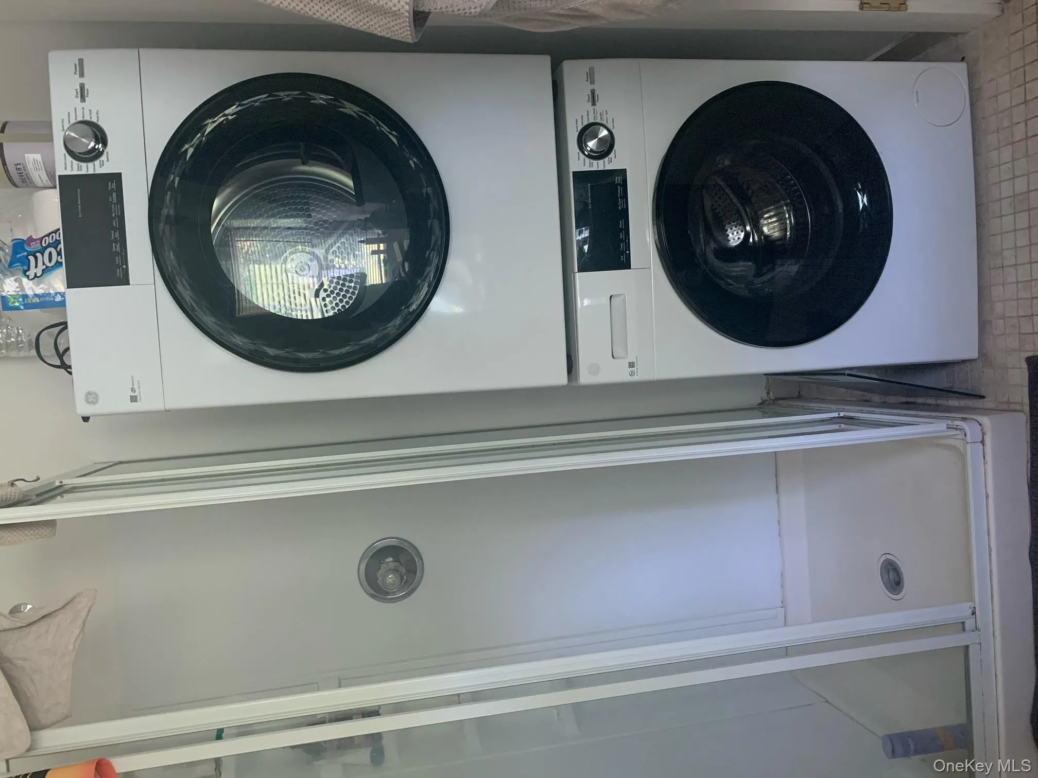 Washroom featuring stacked washer and clothes dryer and tile patterned floors Washroom featuring stacked washer and clothes dryer and tile patterned floors