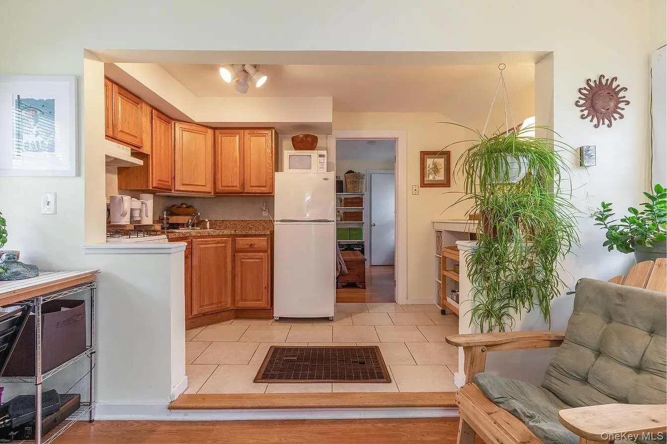Kitchen featuring white appliances, brown cabinetry, under cabinet range hood, and light tile patterned floors Kitchen featuring white appliances, brown cabinetry, under cabinet range hood, and light tile patterned floors