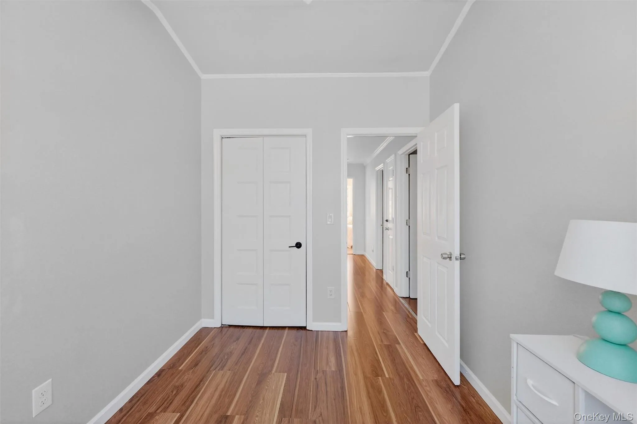 Unfurnished bedroom with dark wood-type flooring, ornamental molding, and a closet Unfurnished bedroom with dark wood-type flooring, ornamental molding, and a closet