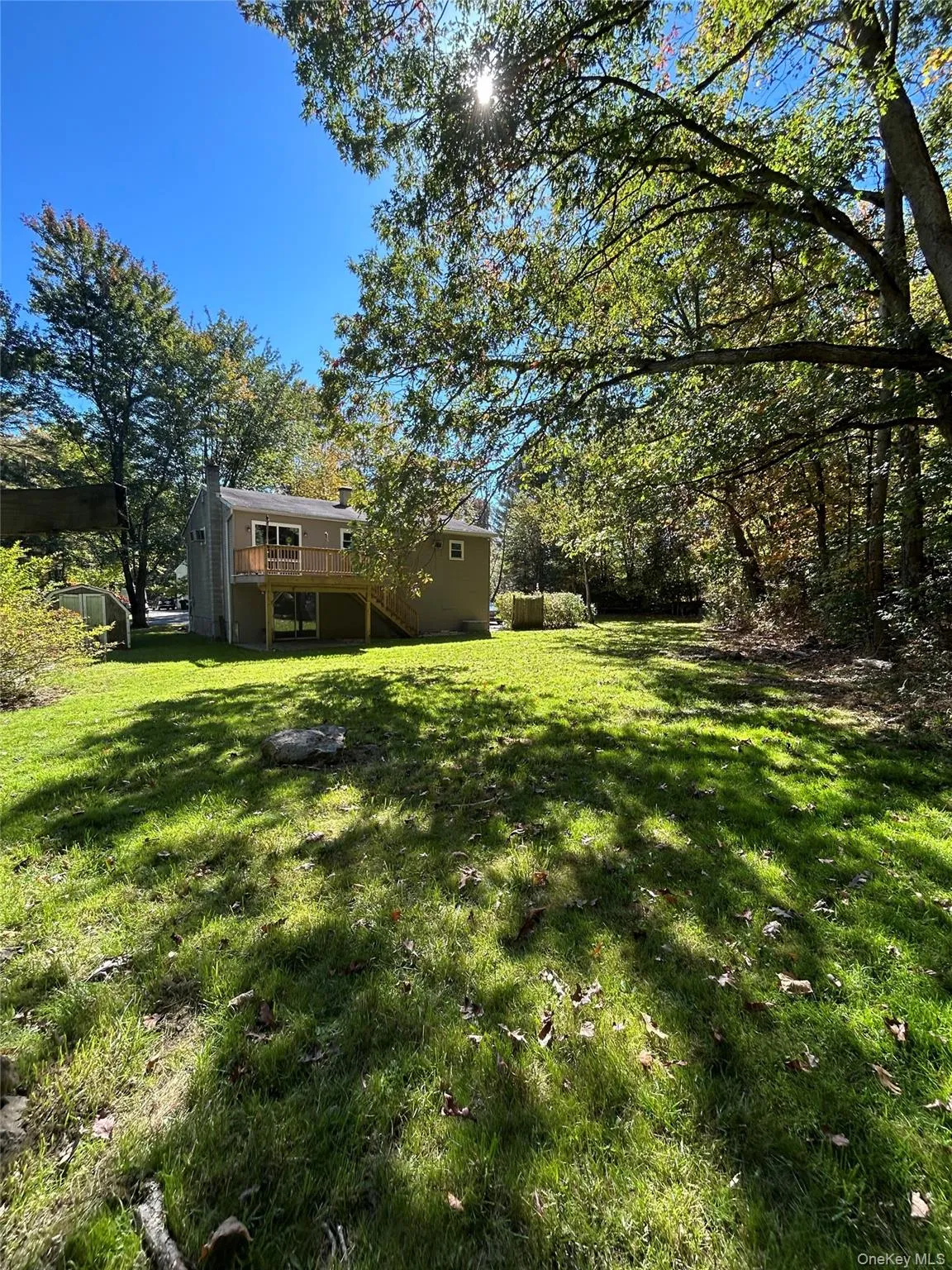 View of green lawn with stairs and a wooden deck View of green lawn with stairs and a wooden deck