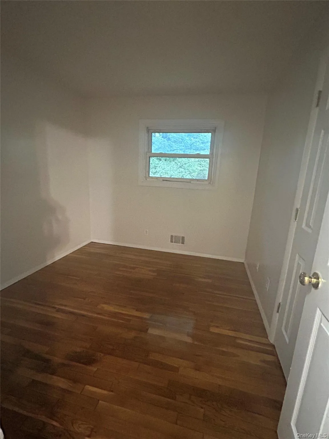 Empty room with dark wood finished floors and baseboards Empty room with dark wood finished floors and baseboards