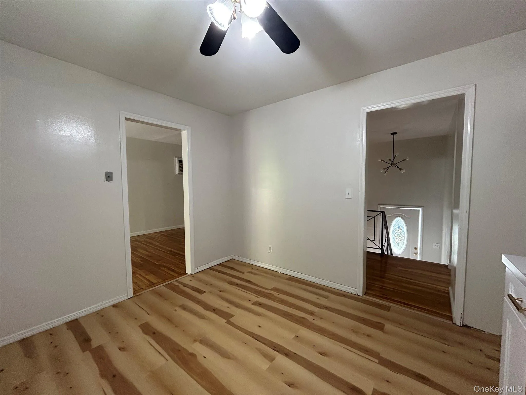Unfurnished room with light wood-style floors, a chandelier, and ceiling fan Unfurnished room with light wood-style floors, a chandelier, and ceiling fan
