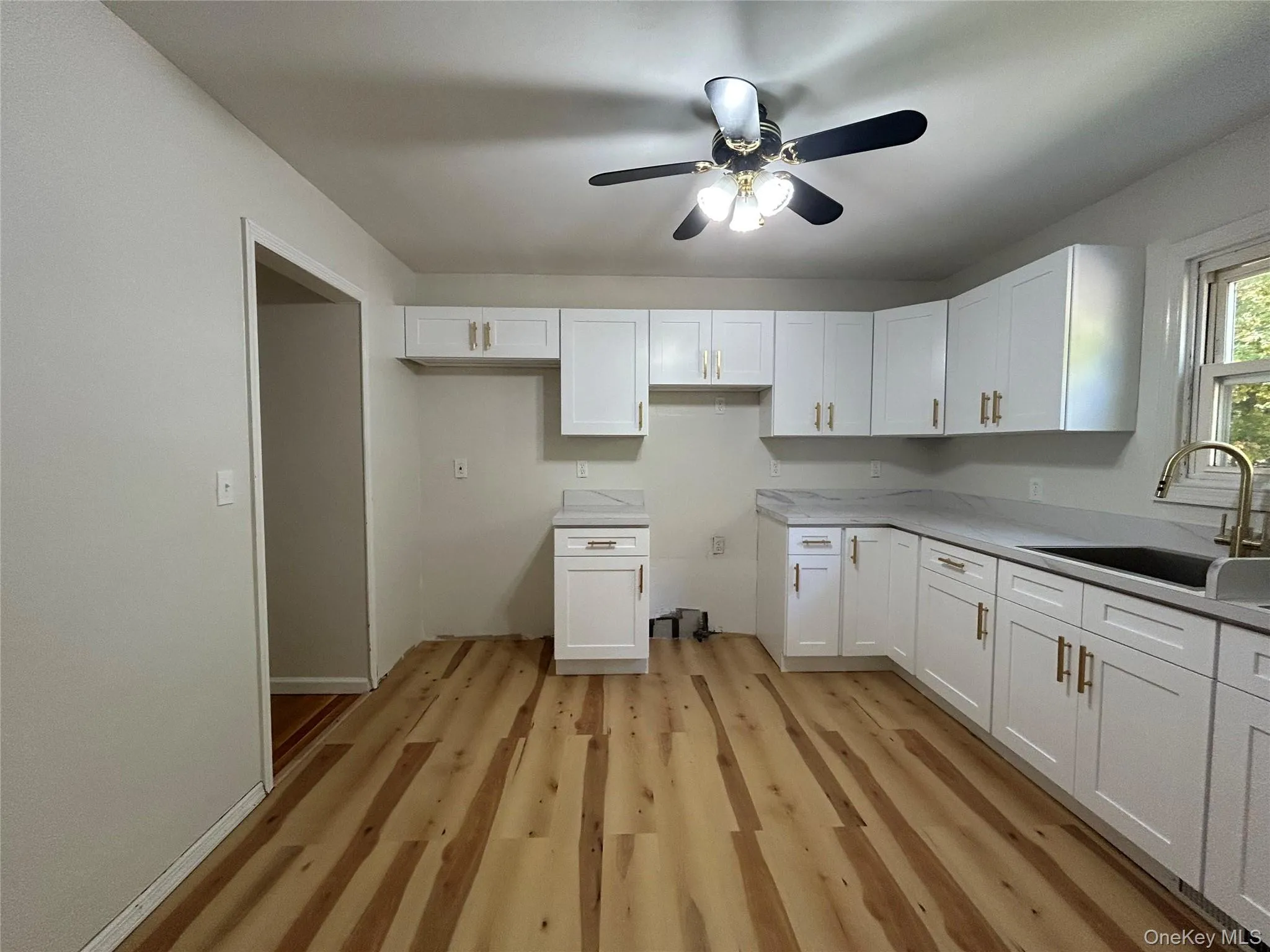 Kitchen featuring light wood-type flooring, white cabinets, and ceiling fan Kitchen featuring light wood-type flooring, white cabinets, and ceiling fan