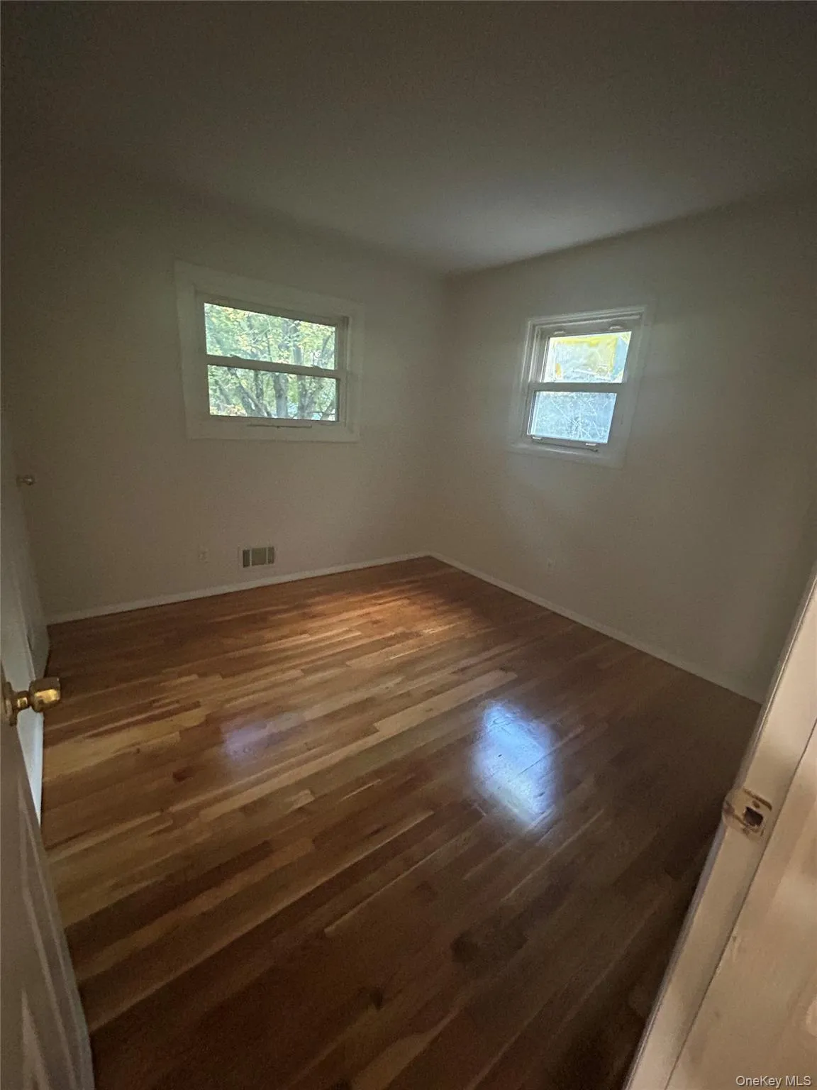 Spare room with baseboards and dark wood-style flooring Spare room with baseboards and dark wood-style flooring