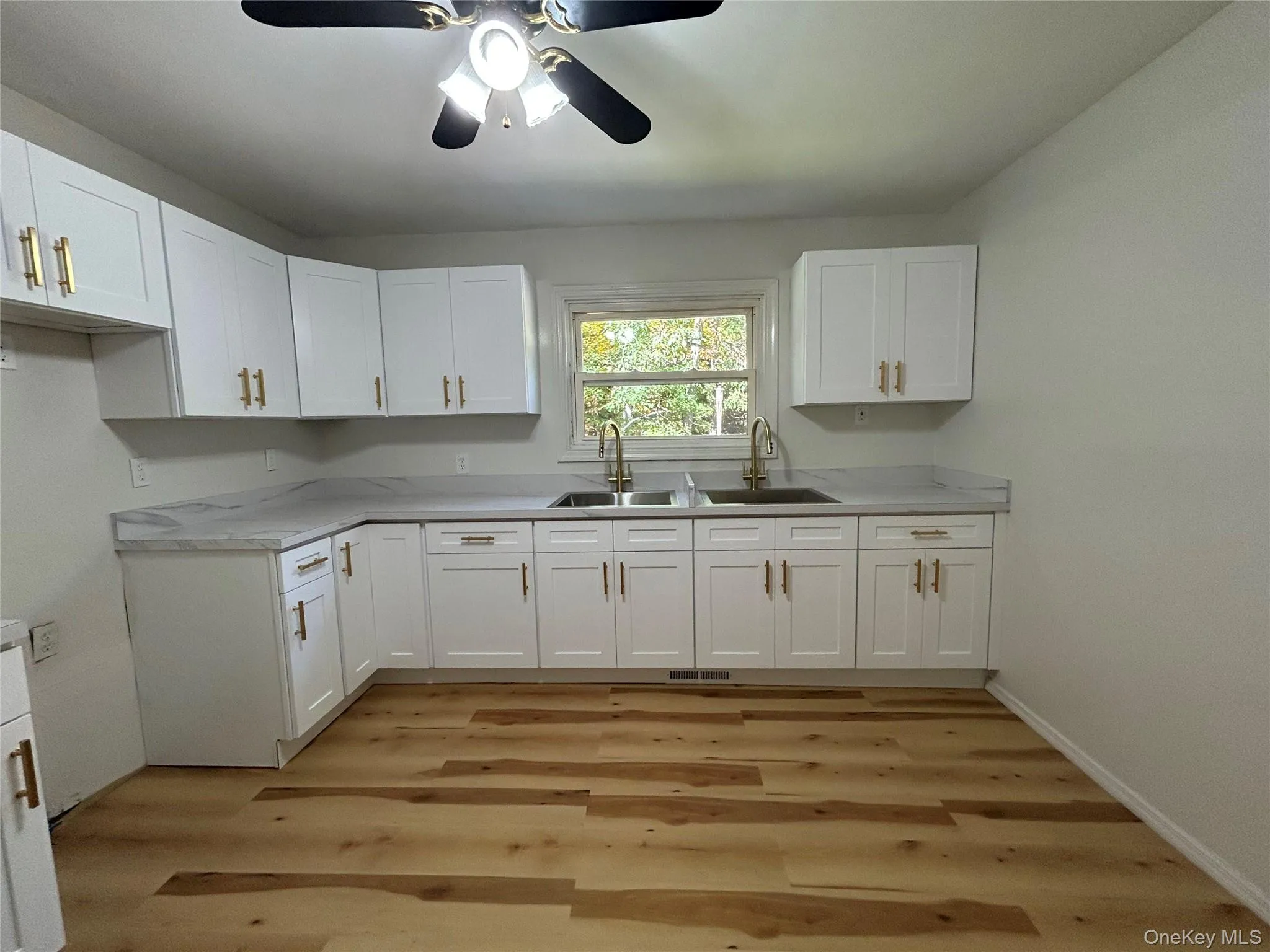 Kitchen with white cabinets, light countertops, light wood-style floors, and ceiling fan Kitchen with white cabinets, light countertops, light wood-style floors, and ceiling fan