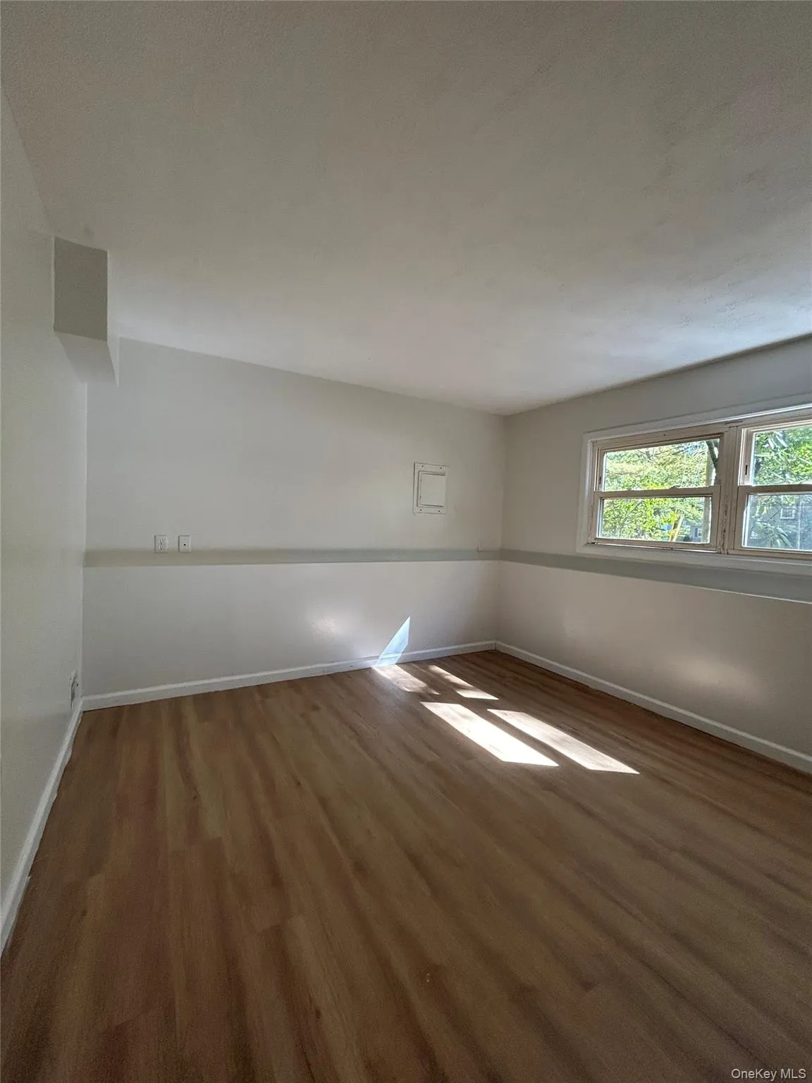 Unfurnished room featuring dark wood-style floors and baseboards Unfurnished room featuring dark wood-style floors and baseboards