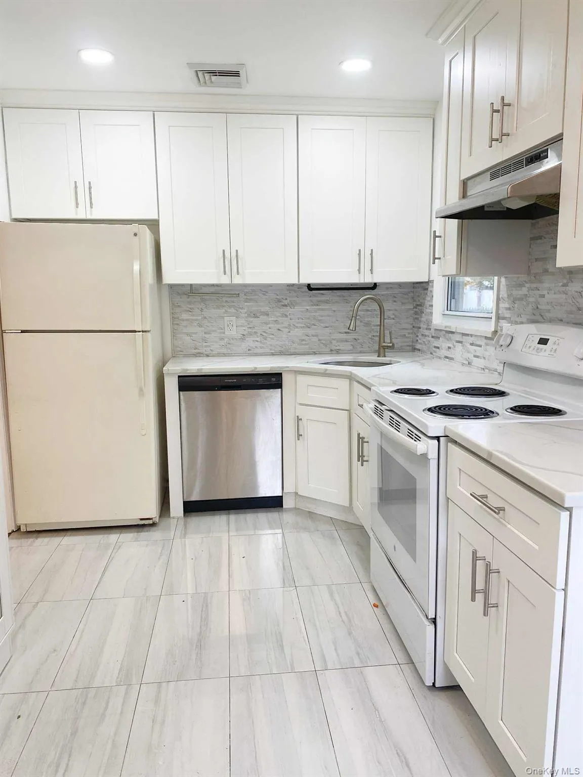 Kitchen featuring white appliances, backsplash, white cabinets, and recessed lighting Kitchen featuring white appliances, backsplash, white cabinets, and recessed lighting
