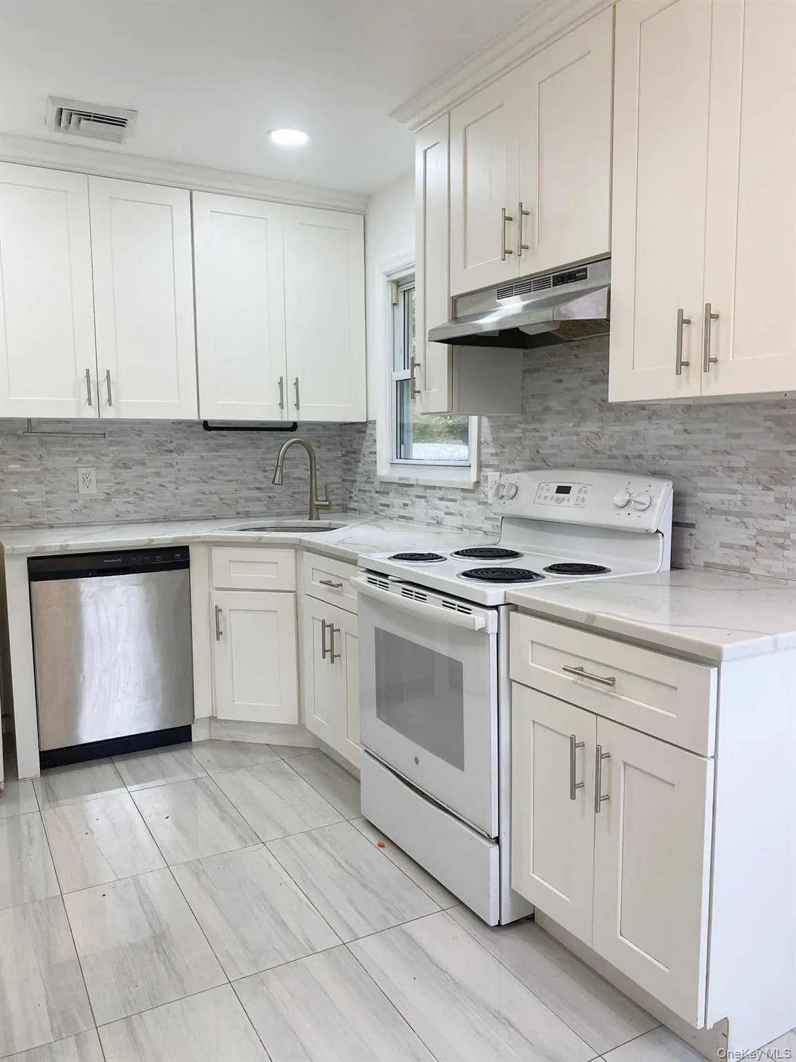 Kitchen with white electric range oven, decorative backsplash, stainless steel dishwasher, white cabinets, and recessed lighting Kitchen with white electric range oven, decorative backsplash, stainless steel dishwasher, white cabinets, and recessed lighting