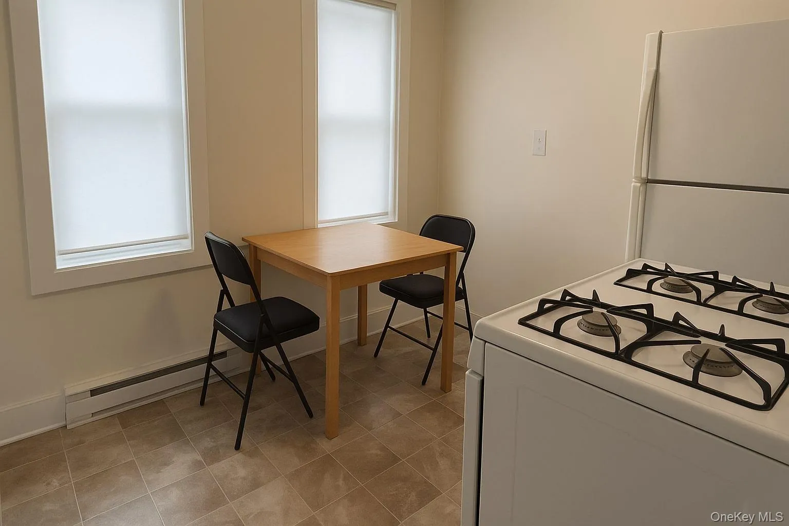 Kitchen featuring white appliances, baseboard heating, and white cabinetry Kitchen featuring white appliances, baseboard heating, and white cabinetry