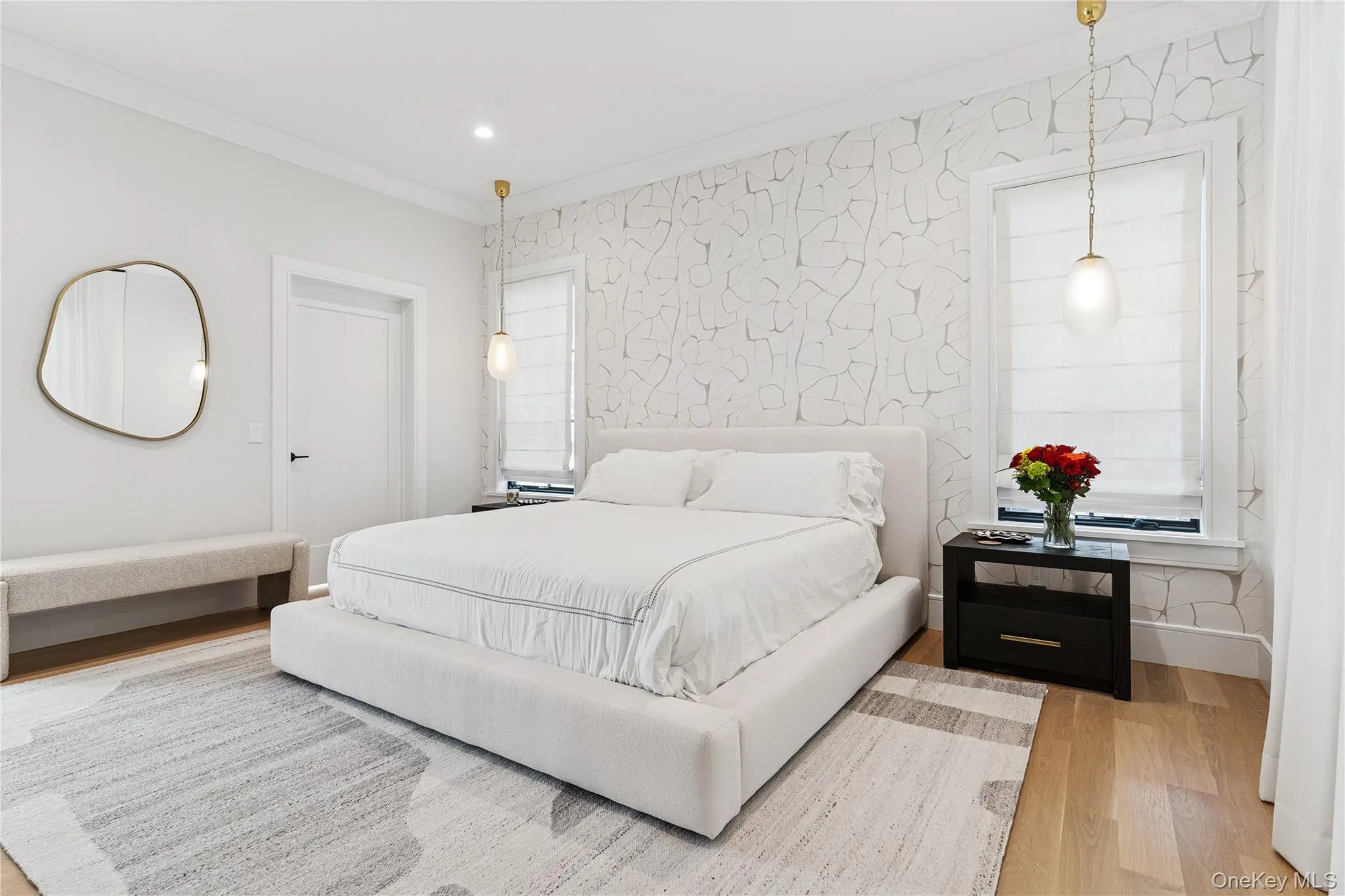 primary Bedroom featuring wood finished floors, wallpapered walls, ornamental molding, recessed lighting, and an accent wall primary Bedroom featuring wood finished floors, wallpapered walls, ornamental molding, recessed lighting, and an accent wall