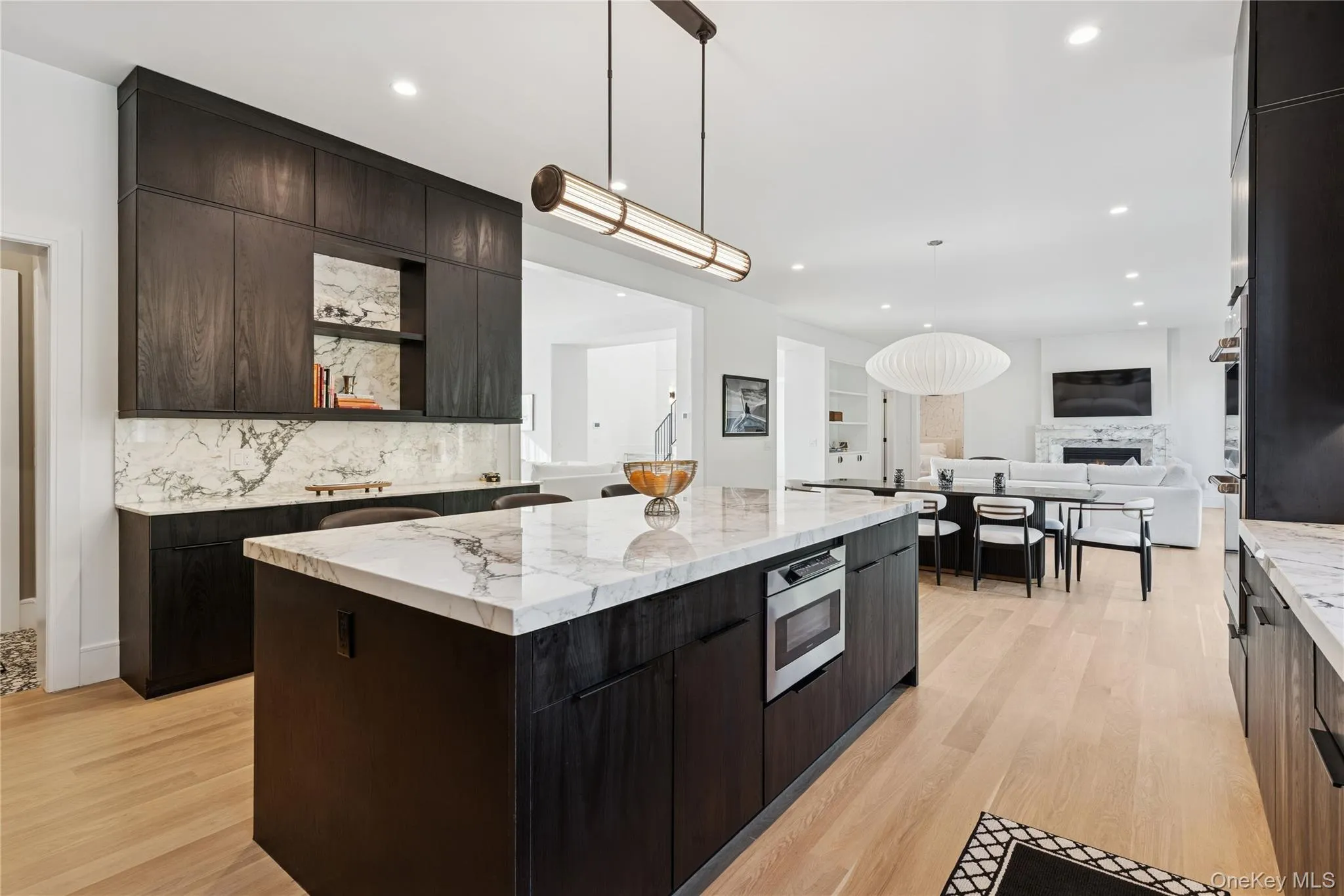 Kitchen featuring open shelves, a fireplace, dark brown cabinetry, light wood-type flooring, and recessed lighting Kitchen featuring open shelves, a fireplace, dark brown cabinetry, light wood-type flooring, and recessed lighting