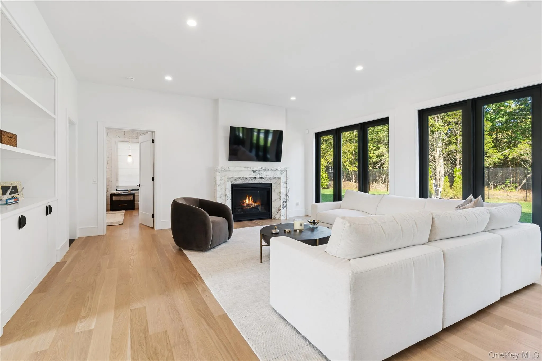 Living area with recessed lighting, light wood-style flooring, and a high end fireplace Living area with recessed lighting, light wood-style flooring, and a high end fireplace