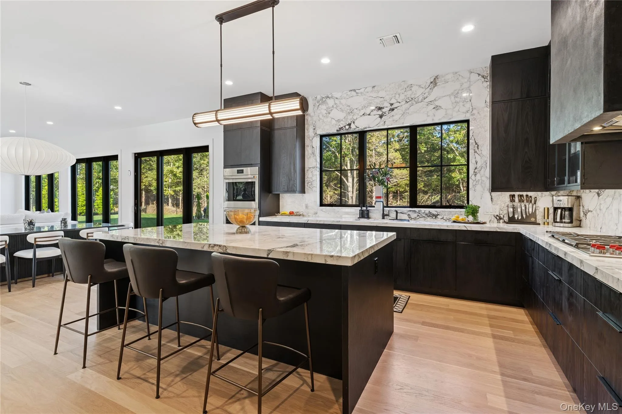 Kitchen featuring tasteful backsplash, decorative light fixtures, a kitchen breakfast bar, light wood-style floors, and recessed lighting Kitchen featuring tasteful backsplash, decorative light fixtures, a kitchen breakfast bar, light wood-style floors, and recessed lighting