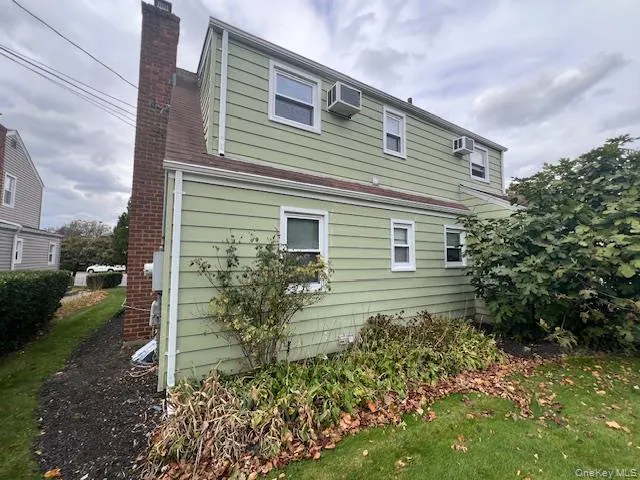 View of property exterior with a chimney, a yard, and a wall unit AC View of property exterior with a chimney, a yard, and a wall unit AC