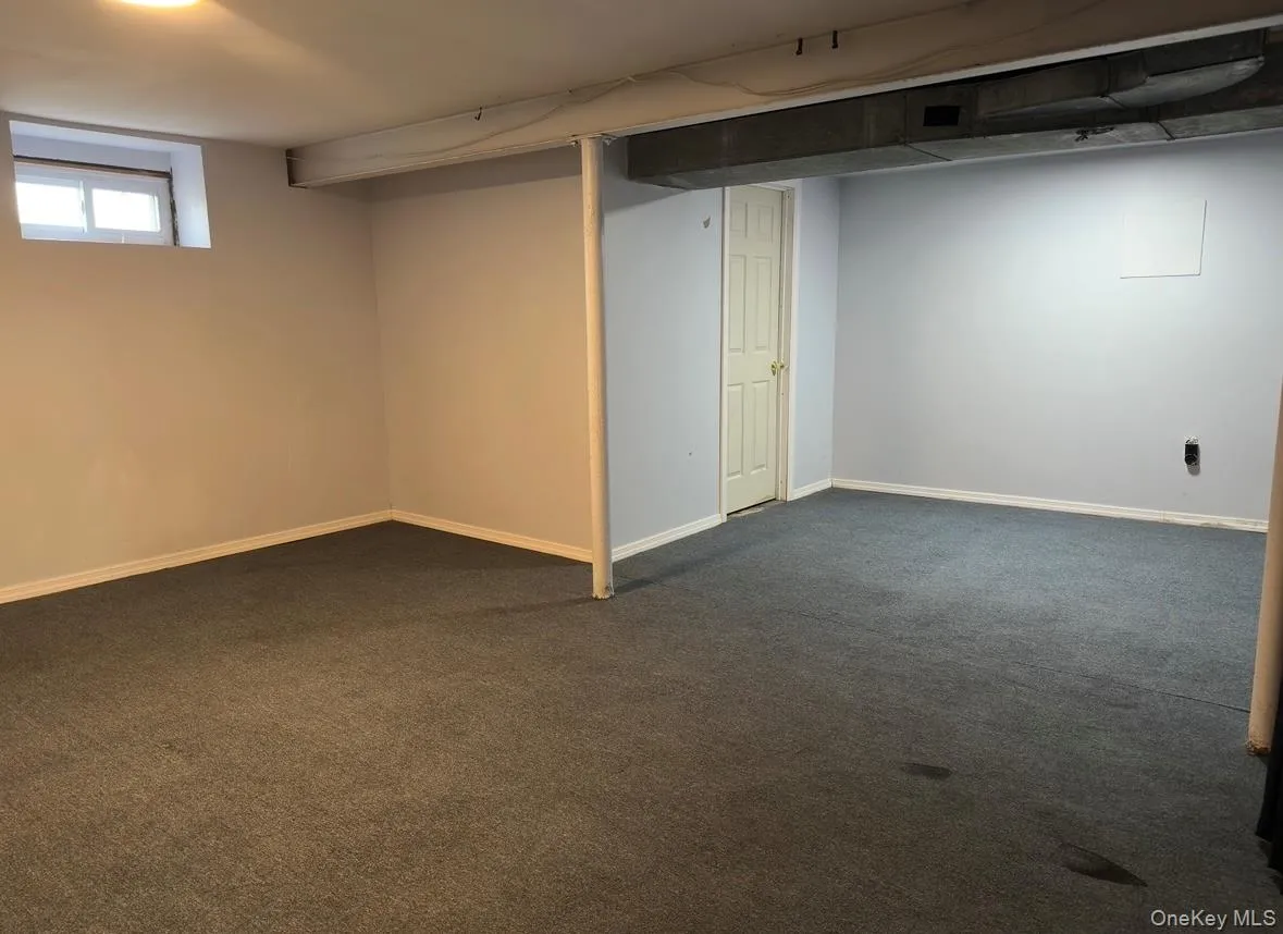 Below grade area with dark colored carpet and baseboards Below grade area with dark colored carpet and baseboards