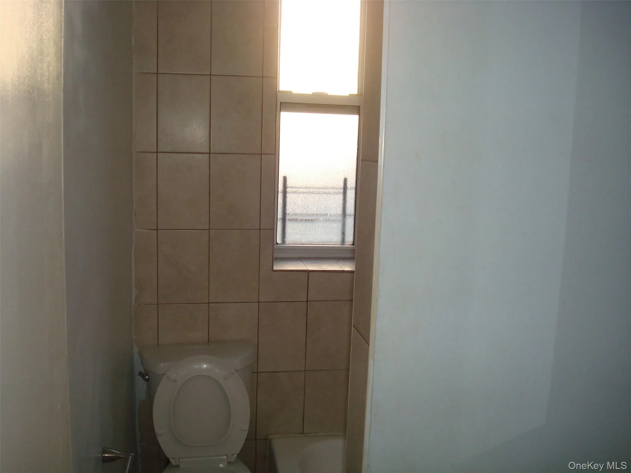 Full bathroom with toilet and tile walls Full bathroom with toilet and tile walls