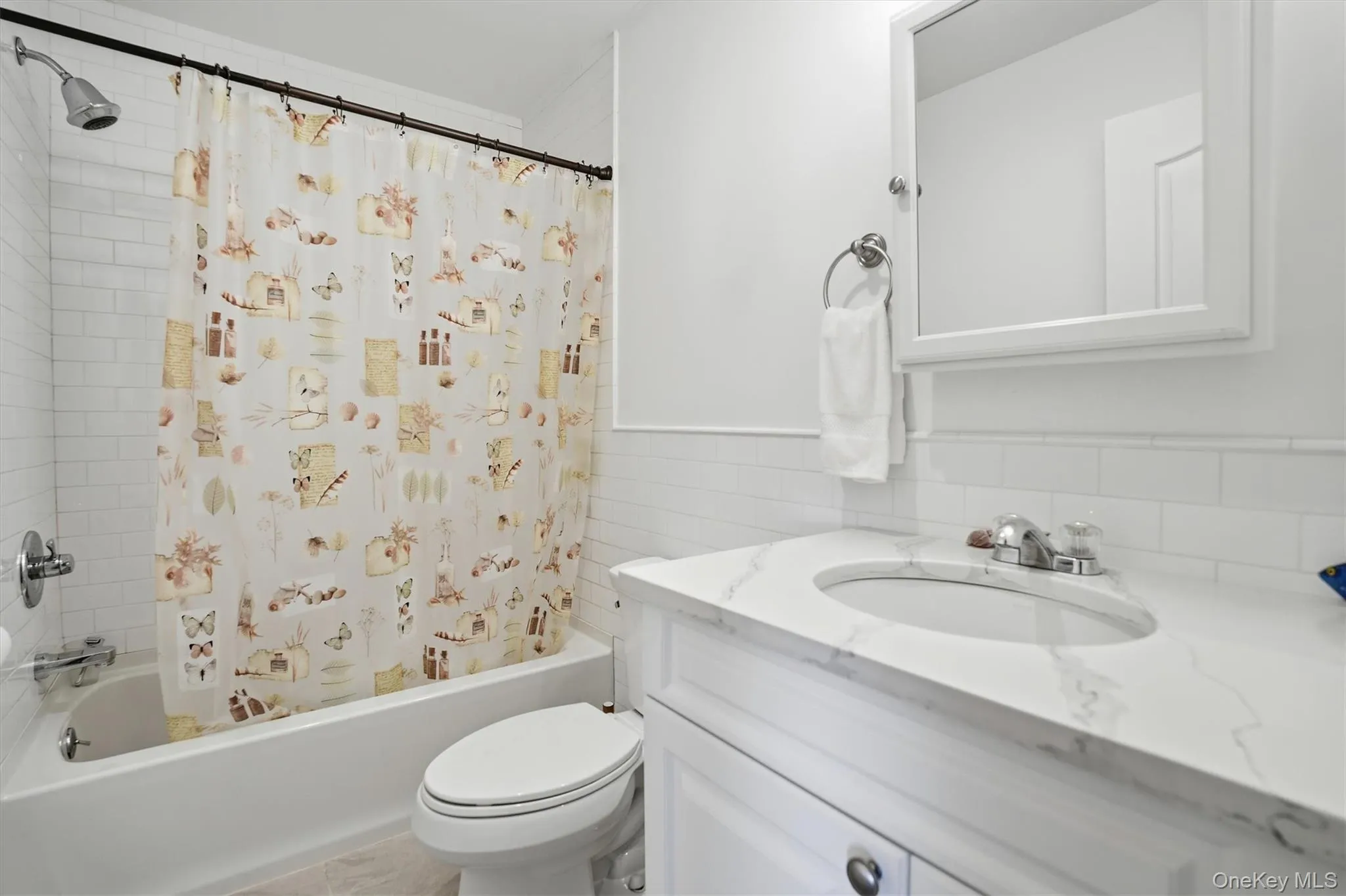 Bathroom featuring shower / bath combo, vanity, tile walls, and backsplash Bathroom featuring shower / bath combo, vanity, tile walls, and backsplash