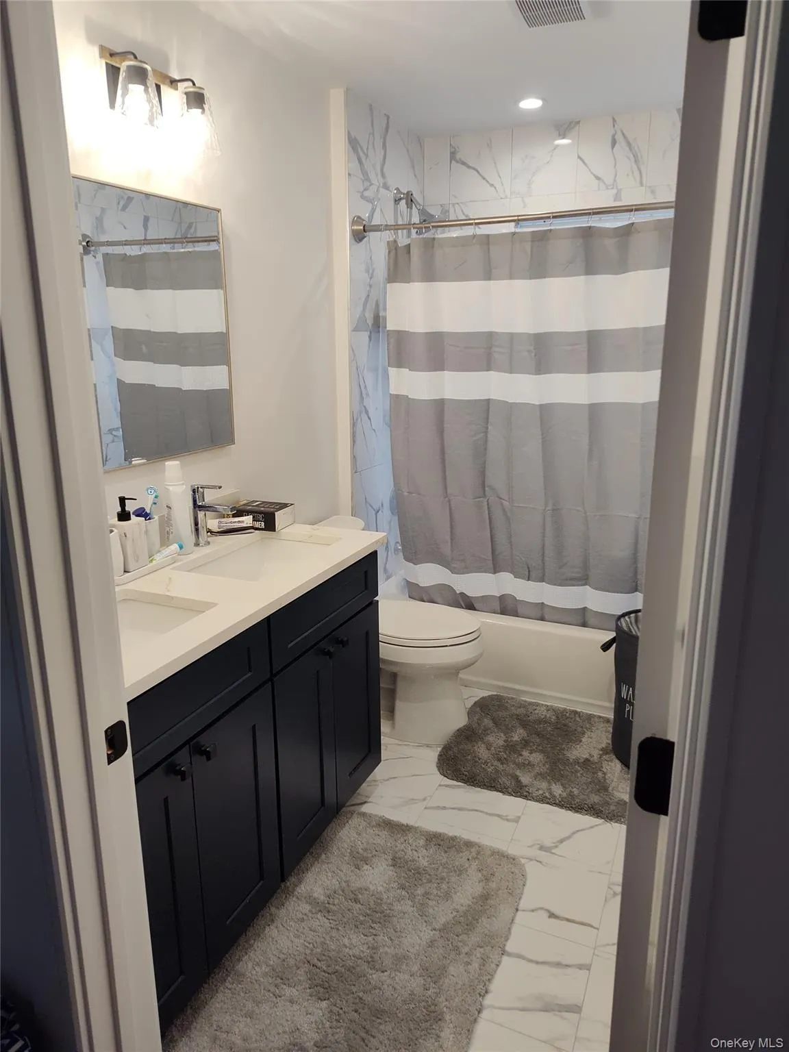 Full family bath with double vanity, shower / tub combo with curtain, and light tile finish flooring Full family bath with double vanity, shower / tub combo with curtain, and light tile finish flooring