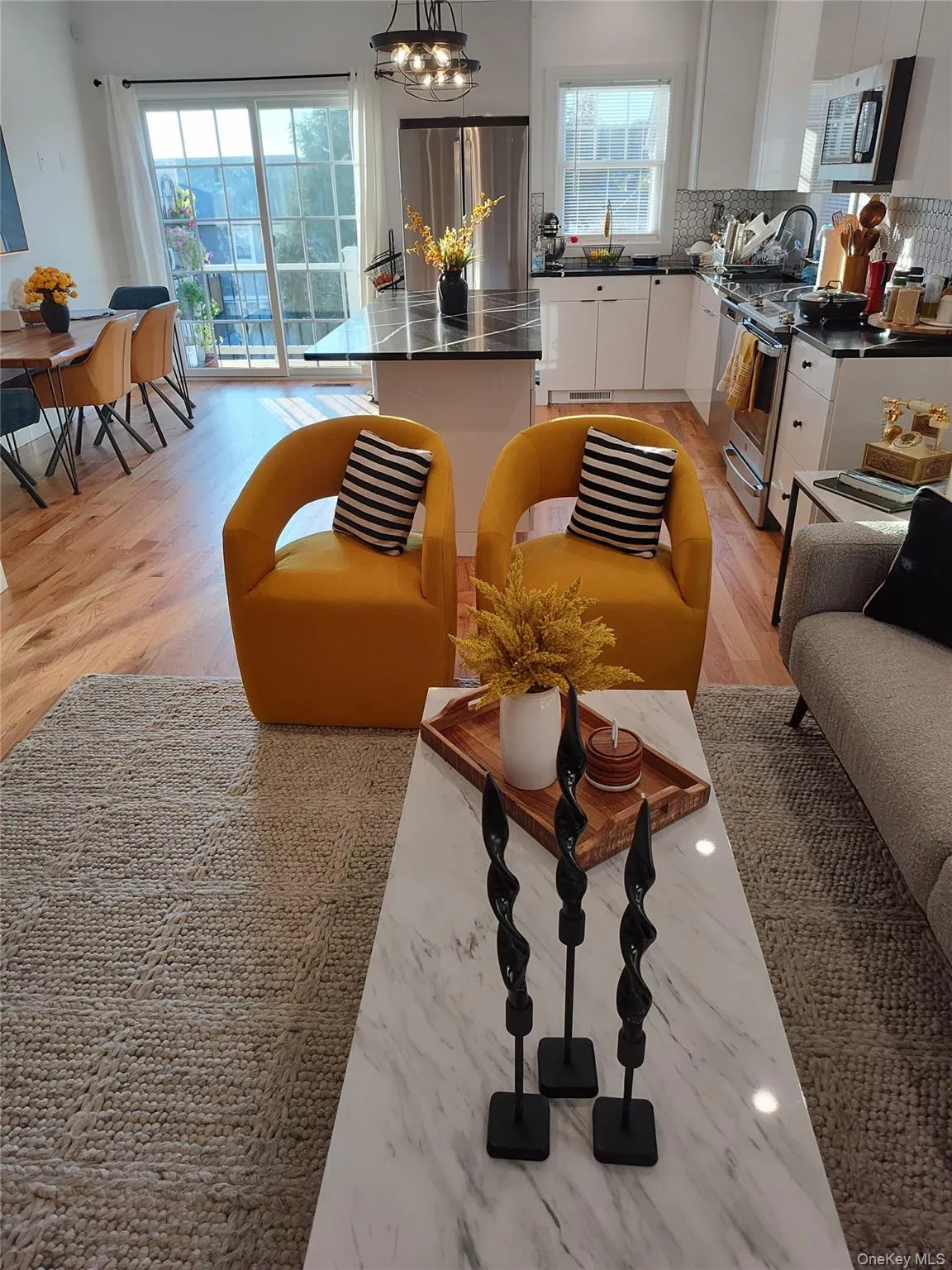 Living room with healthy amount of natural light, light wood finished floors, and a chandelier Living room with healthy amount of natural light, light wood finished floors, and a chandelier