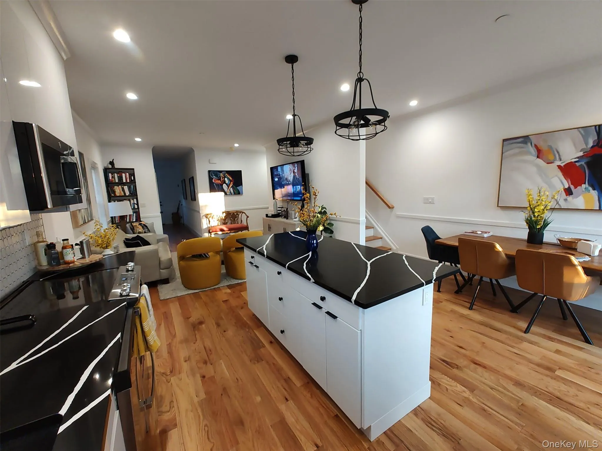 Kitchen with white cabinetry, dark countertops, light wood finished floors, range with electric stovetop, and decorative light fixtures Kitchen with white cabinetry, dark countertops, light wood finished floors, range with electric stovetop, and decorative light fixtures