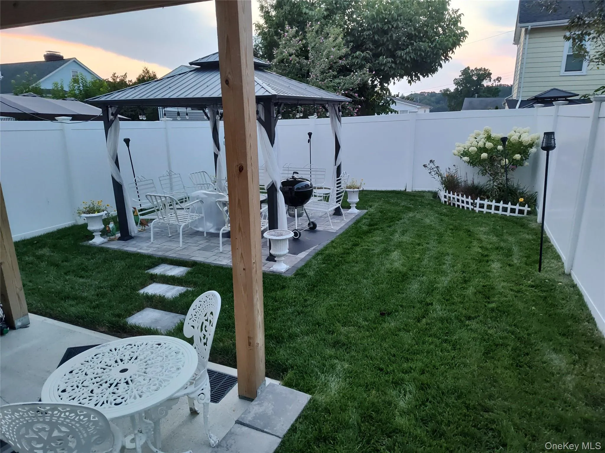 Yard at dusk with a gazebo, a patio, and a fenced backyard Yard at dusk with a gazebo, a patio, and a fenced backyard