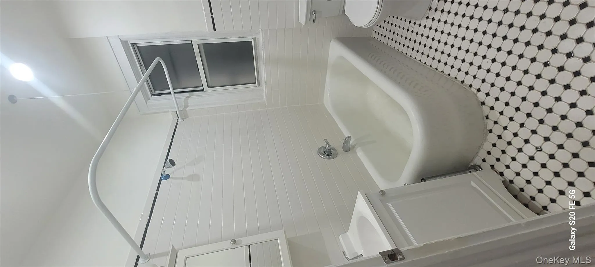Bathroom with tile walls, vanity, bathtub / shower combination, and light tile patterned floors Bathroom with tile walls, vanity, bathtub / shower combination, and light tile patterned floors