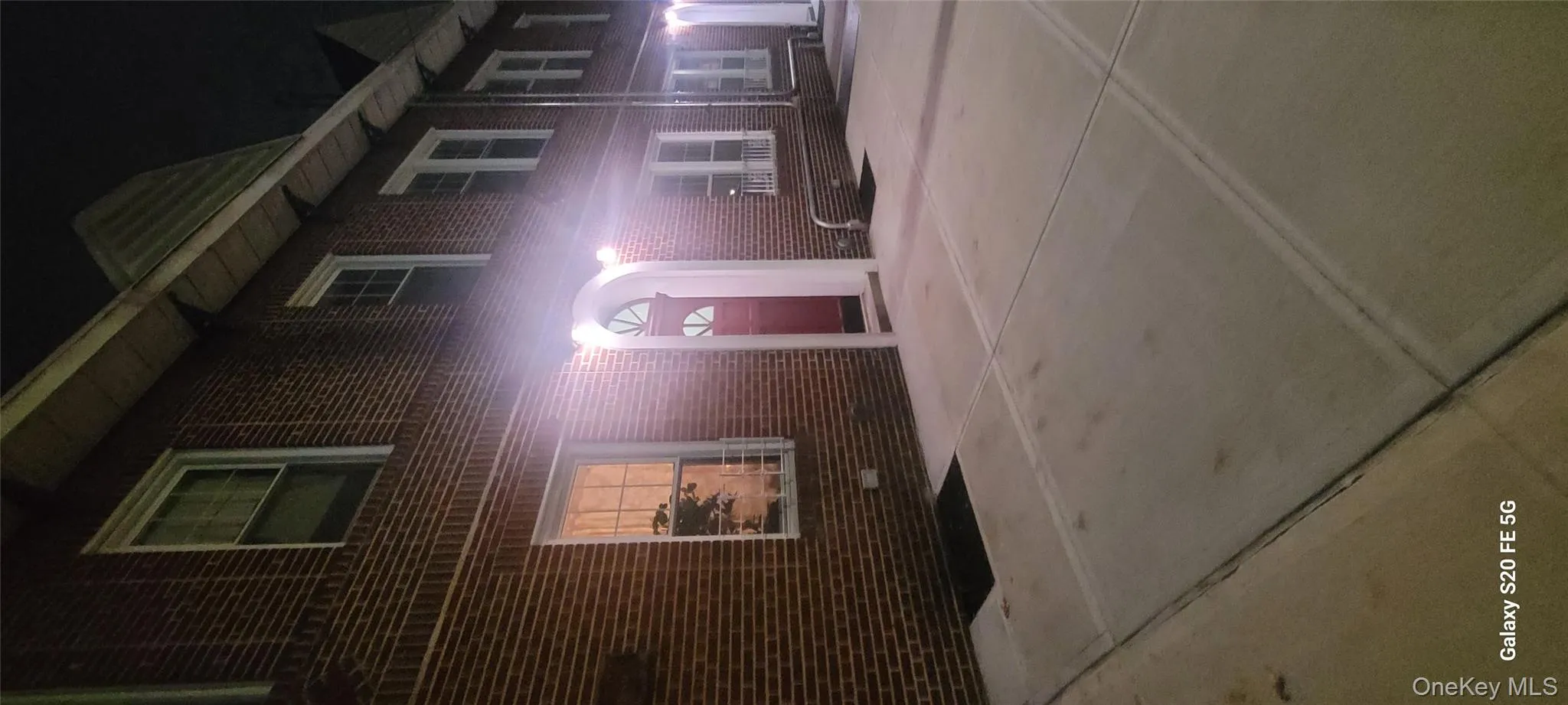Exterior red door entry at night featuring brick siding Exterior red door entry at night featuring brick siding