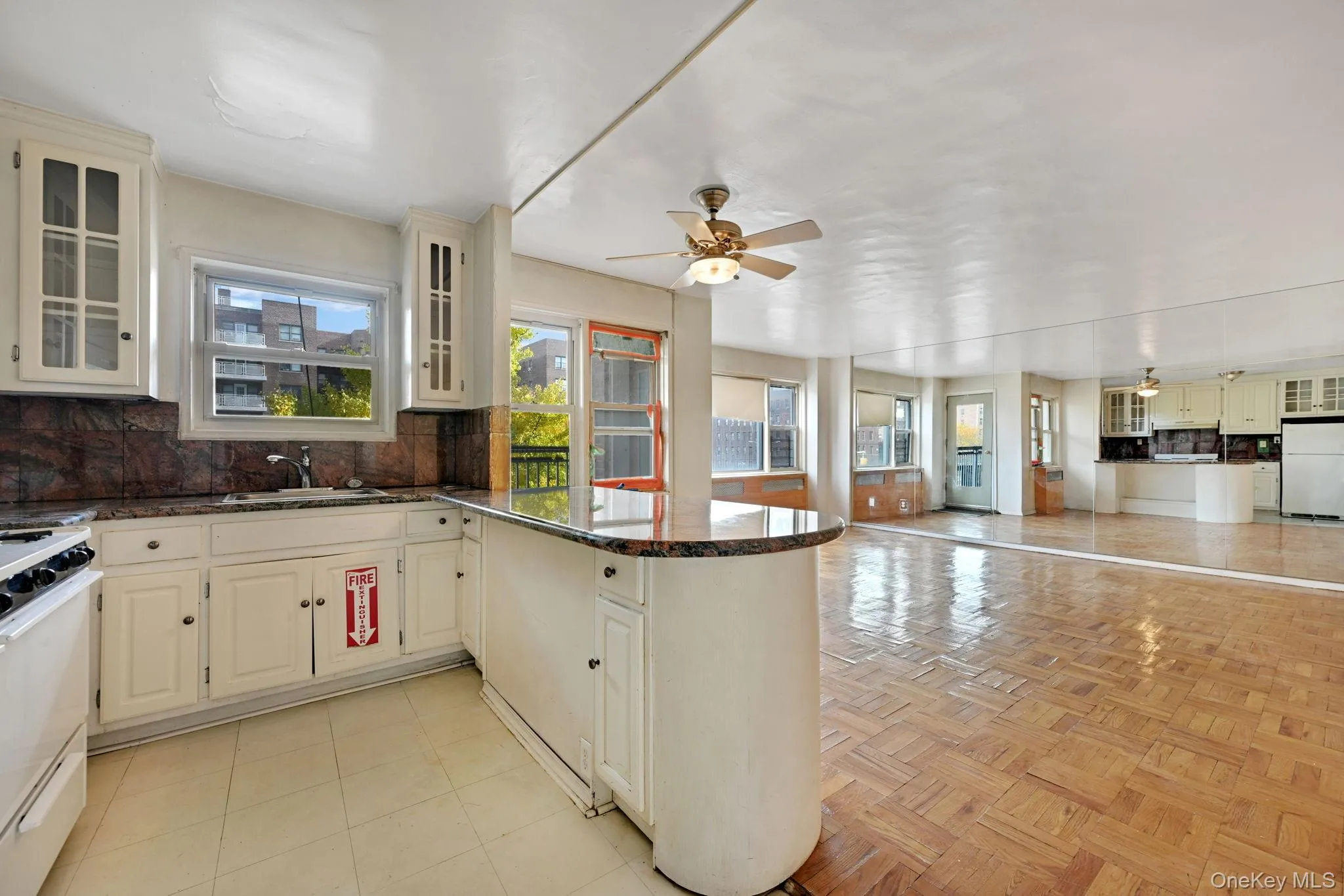 Kitchen with backsplash, glass insert cabinets, a peninsula, cream cabinetry, and white appliances Kitchen with backsplash, glass insert cabinets, a peninsula, cream cabinetry, and white appliances
