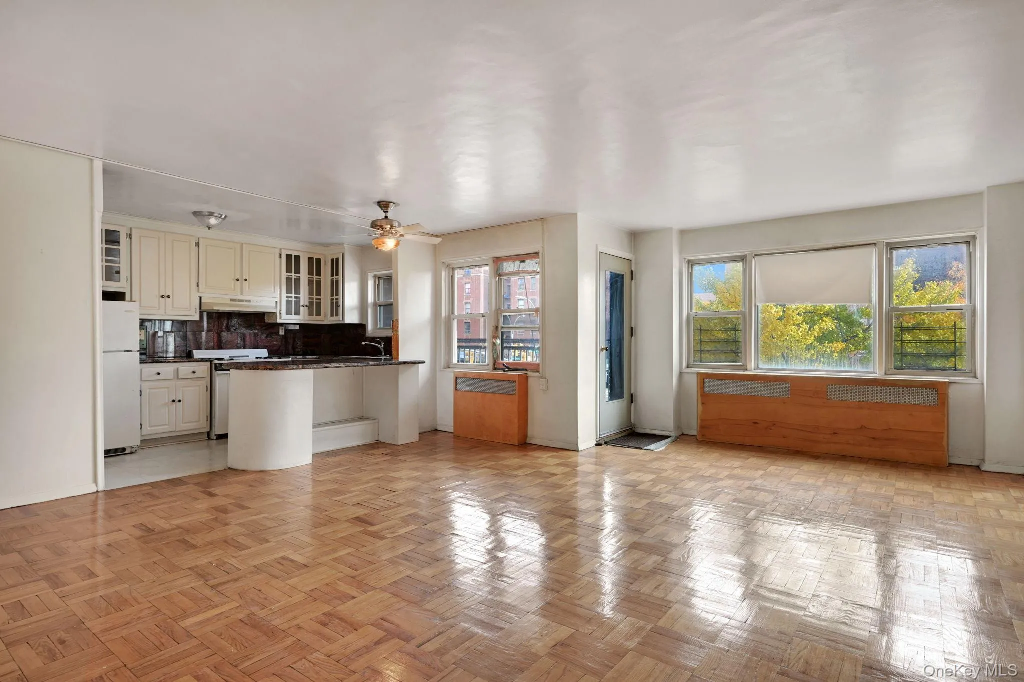Kitchen featuring open floor plan, a peninsula, decorative backsplash, freestanding refrigerator, and glass insert cabinets Kitchen featuring open floor plan, a peninsula, decorative backsplash, freestanding refrigerator, and glass insert cabinets