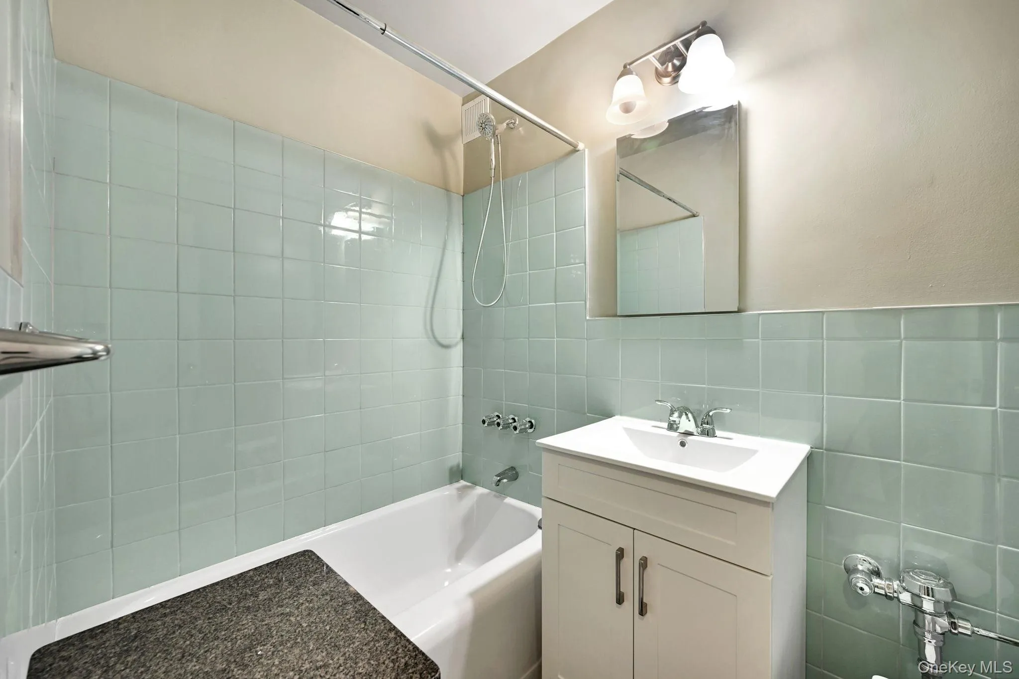 Bathroom with vanity, shower / tub combination, and tile walls Bathroom with vanity, shower / tub combination, and tile walls