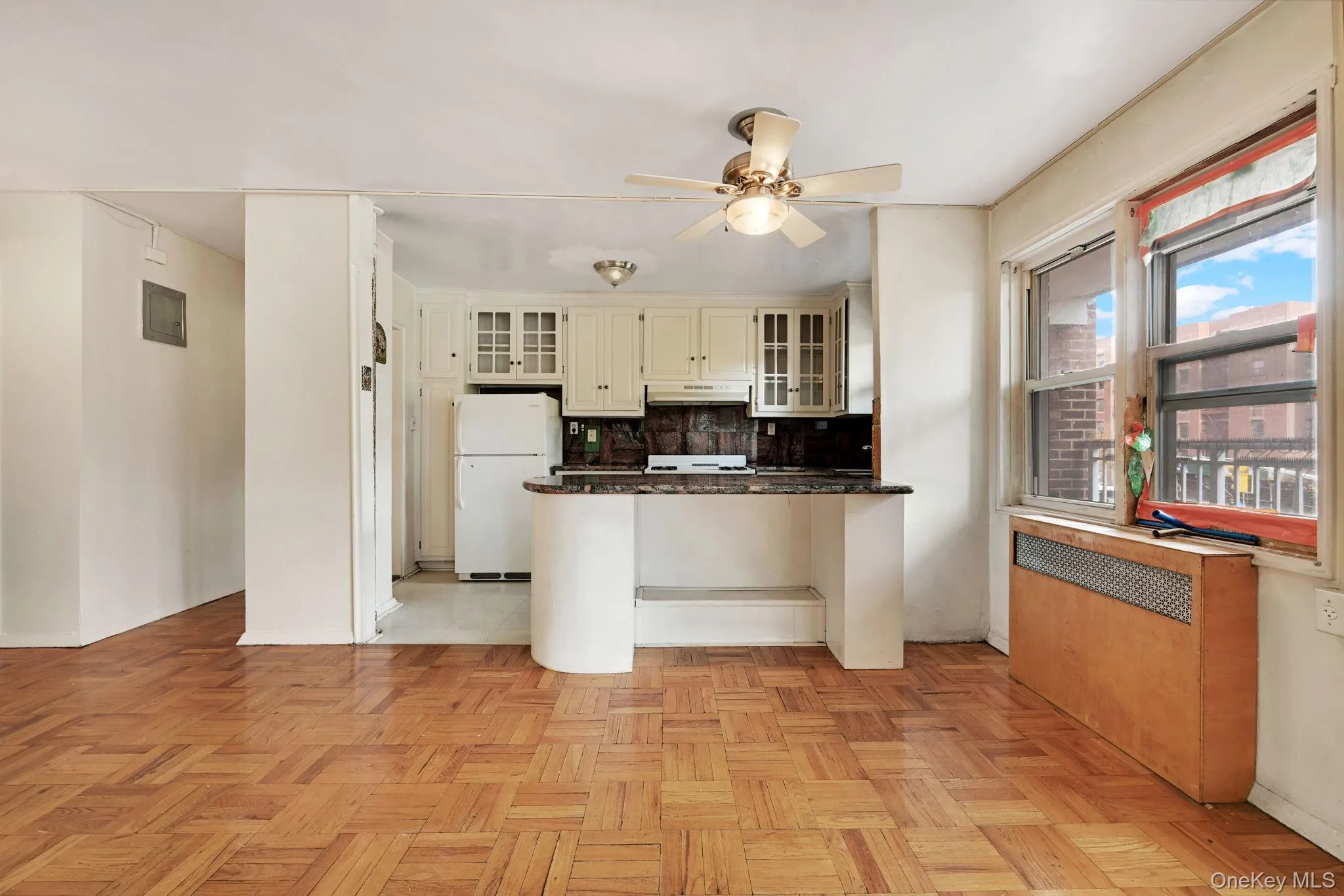 Kitchen featuring radiator, freestanding refrigerator, a peninsula, backsplash, and glass insert cabinets Kitchen featuring radiator, freestanding refrigerator, a peninsula, backsplash, and glass insert cabinets