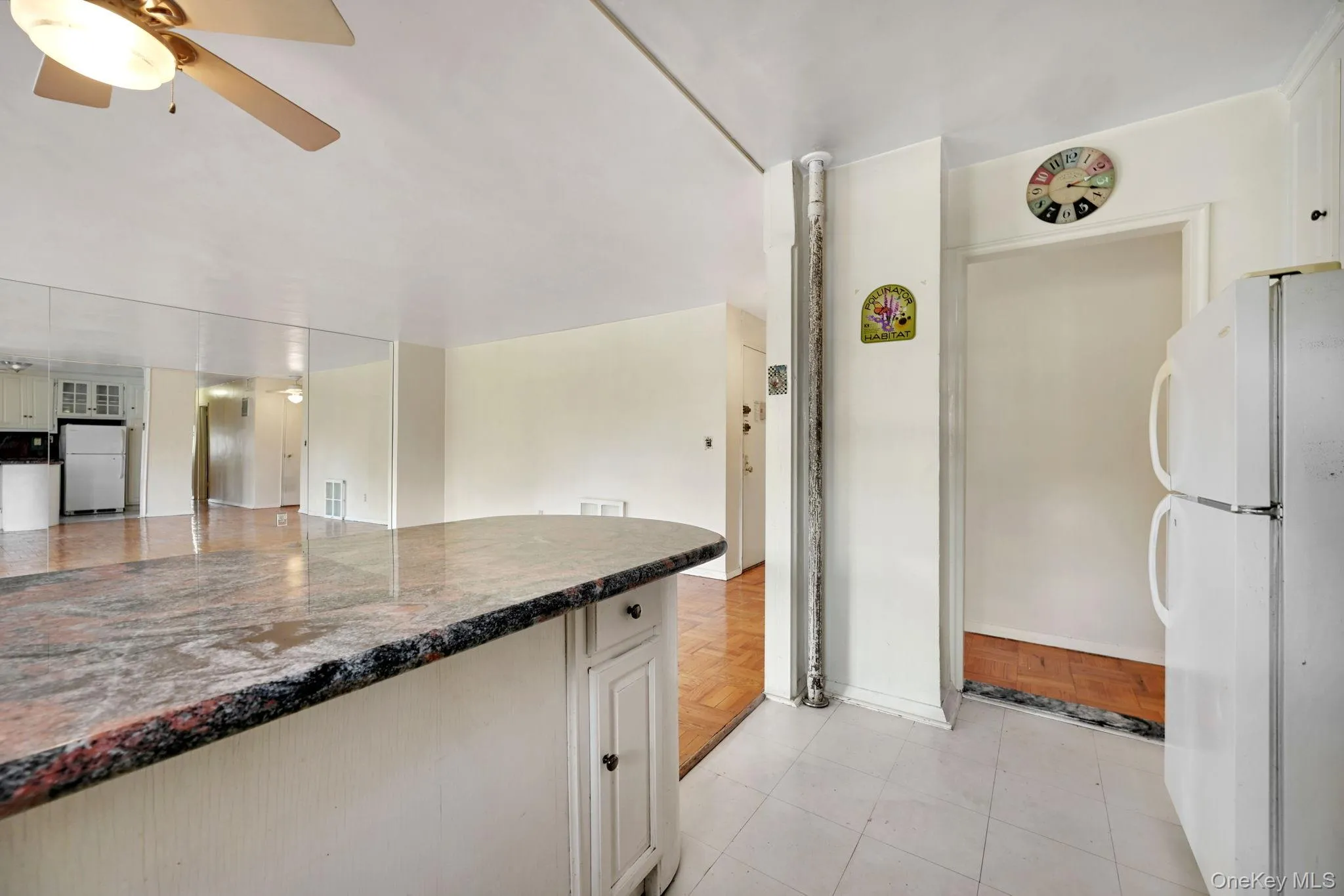 Kitchen with freestanding refrigerator, a ceiling fan, white cabinetry, and light tile patterned floors Kitchen with freestanding refrigerator, a ceiling fan, white cabinetry, and light tile patterned floors