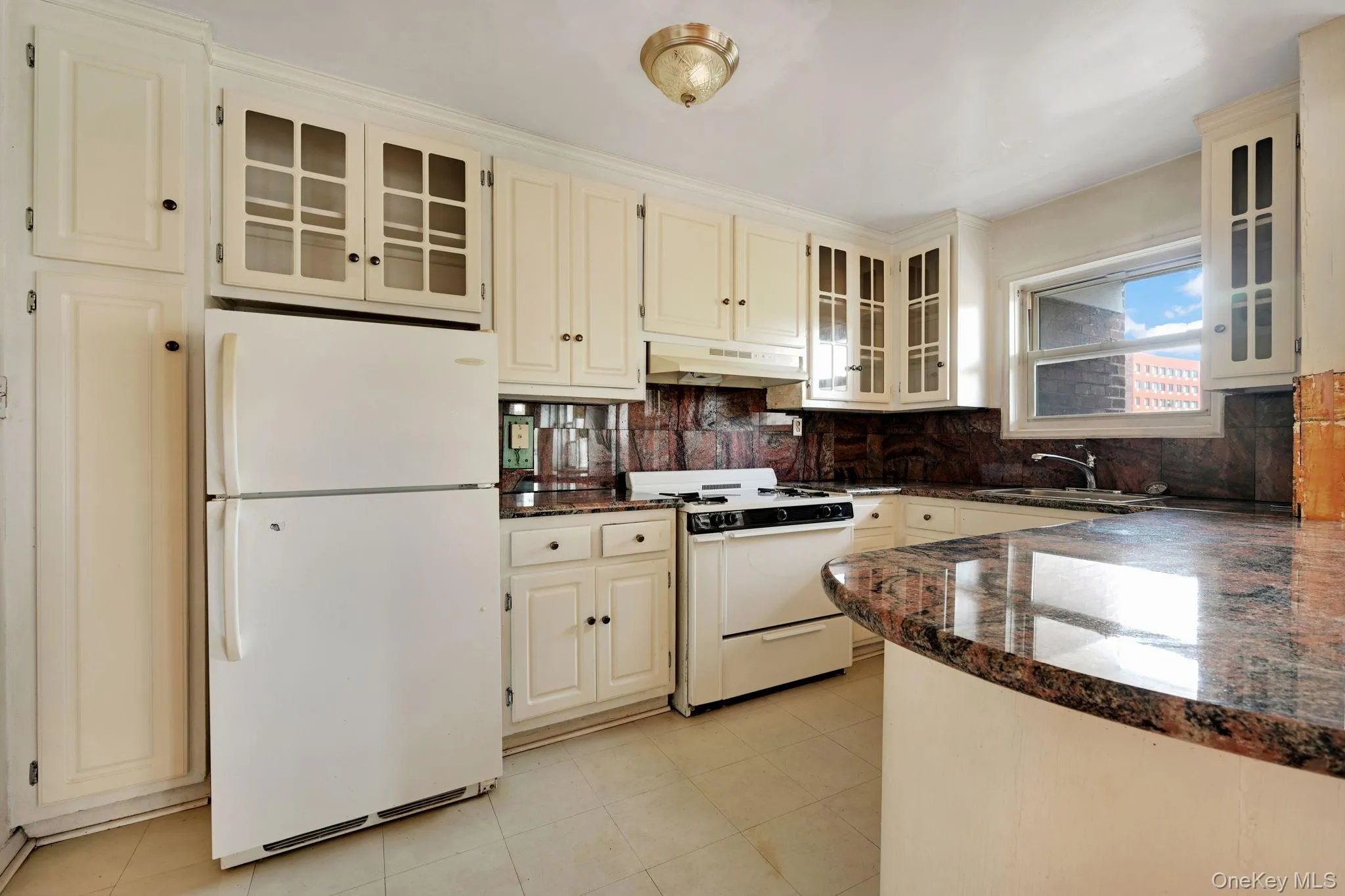 Kitchen with glass insert cabinets, white appliances, and backsplash Kitchen with glass insert cabinets, white appliances, and backsplash