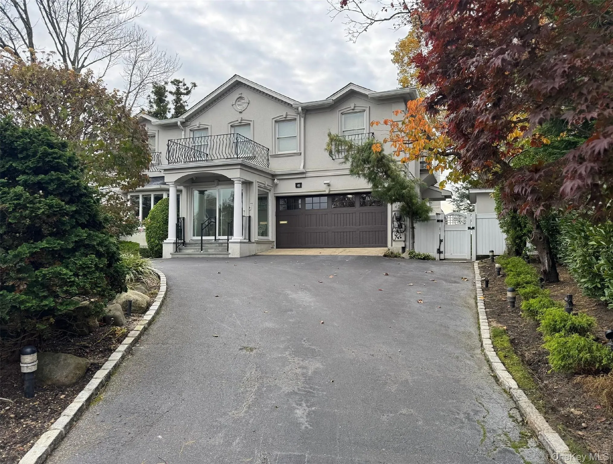 View of front of house with a gate, stucco siding, driveway, a garage, and a balcony View of front of house with a gate, stucco siding, driveway, a garage, and a balcony