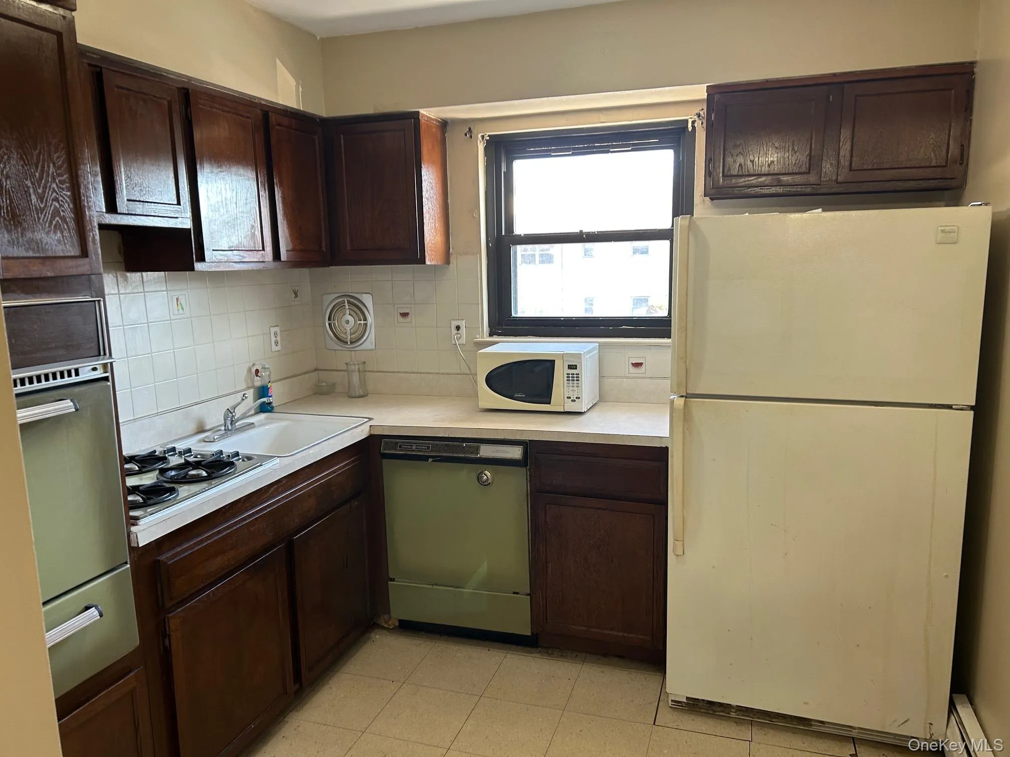 Kitchen featuring dark brown cabinetry, stainless steel appliances, and light countertops Kitchen featuring dark brown cabinetry, stainless steel appliances, and light countertops