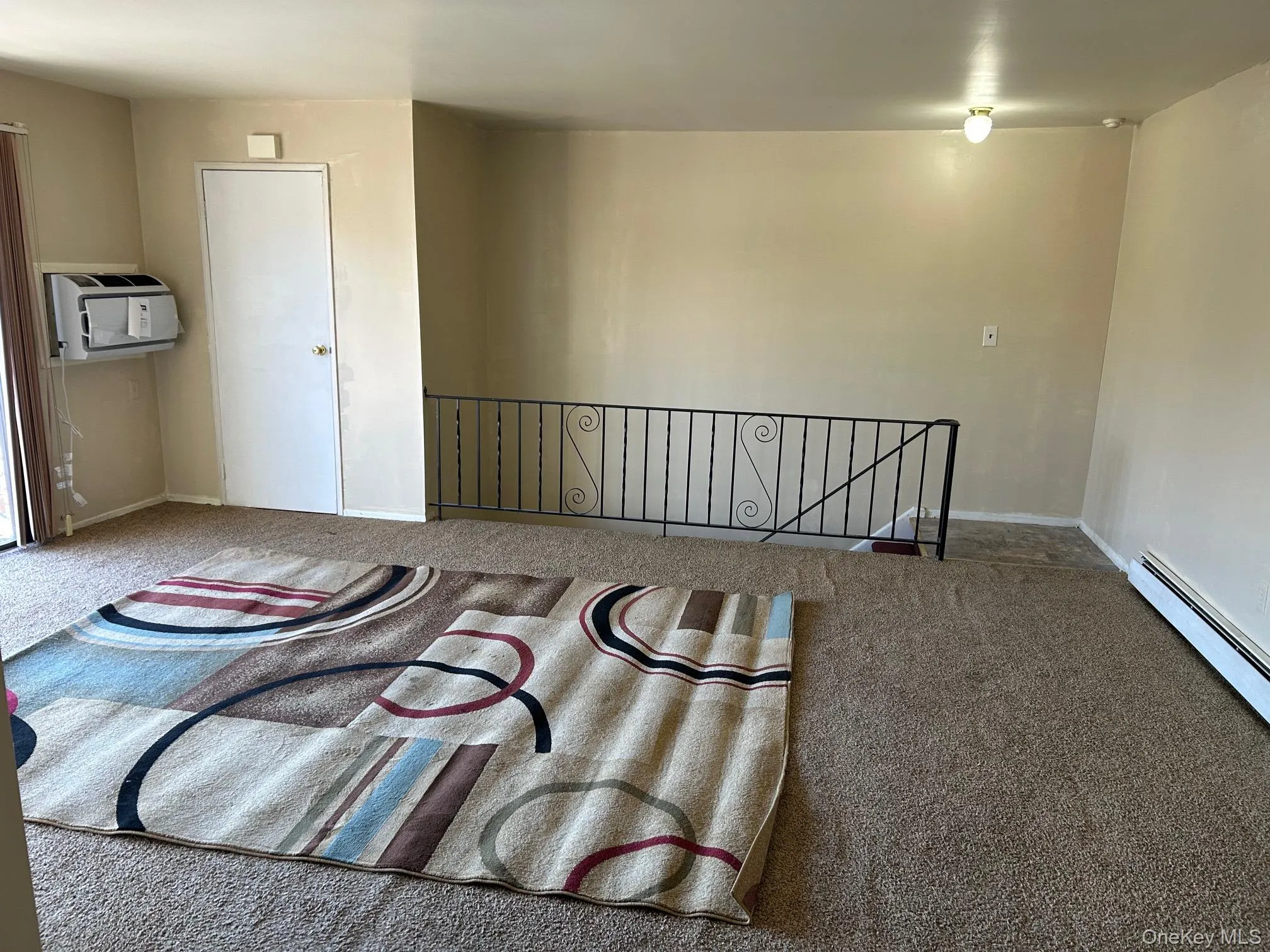 Empty room with carpet flooring and a baseboard radiator Empty room with carpet flooring and a baseboard radiator