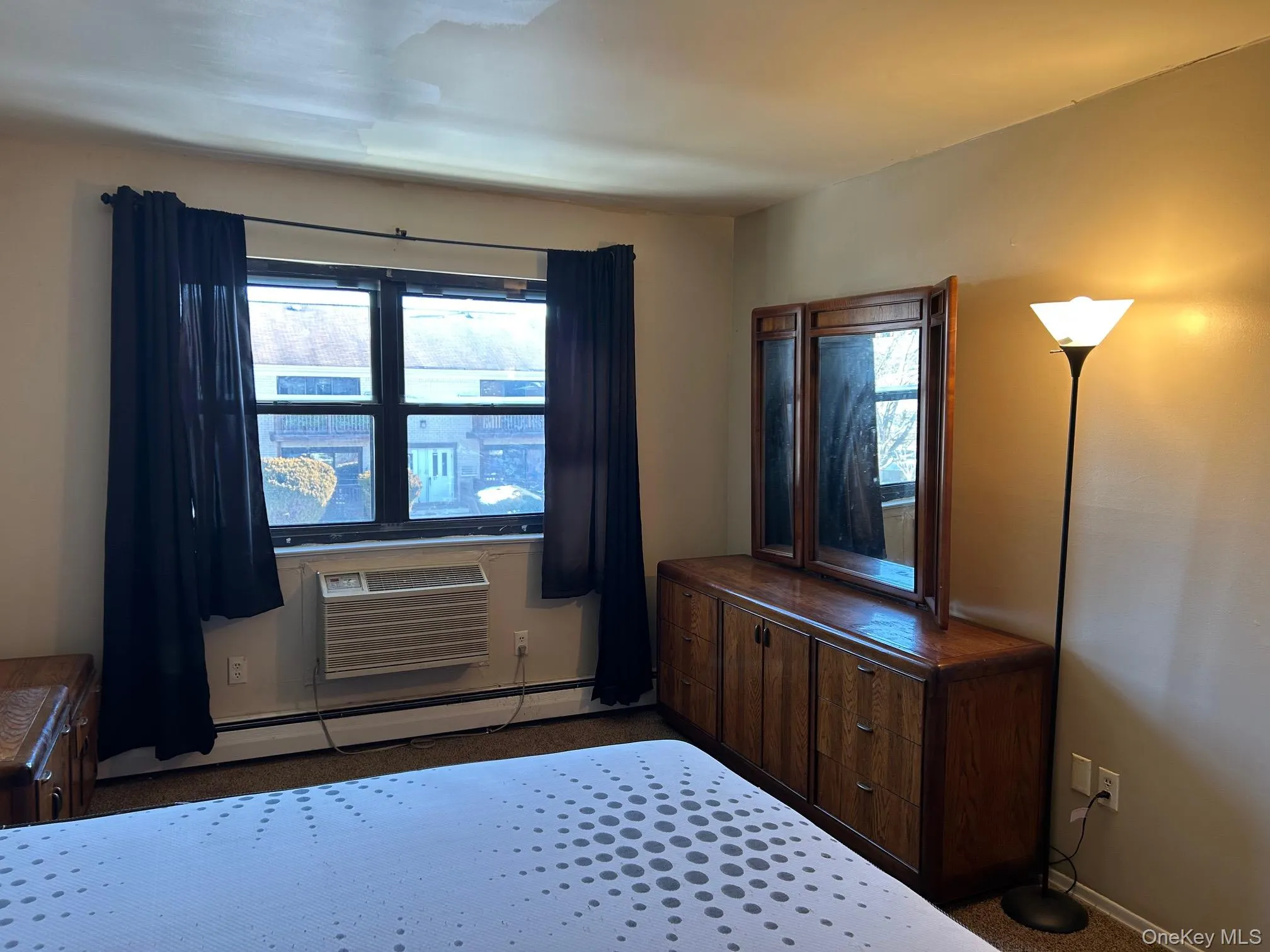 Bedroom with baseboard heating, multiple windows, and a wall mounted AC Bedroom with baseboard heating, multiple windows, and a wall mounted AC