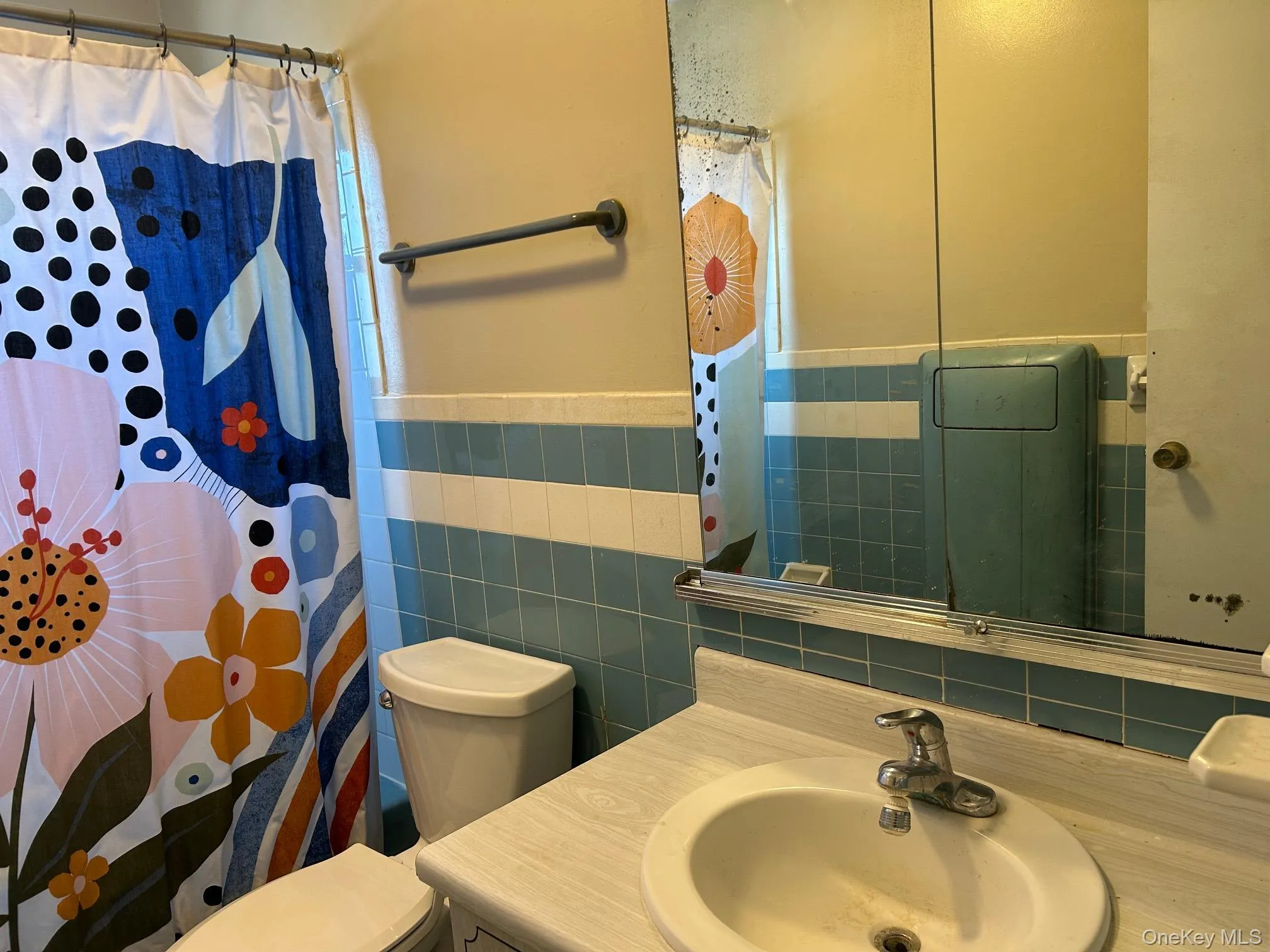 Full bath featuring vanity, a shower with shower curtain, and tile walls Full bath featuring vanity, a shower with shower curtain, and tile walls