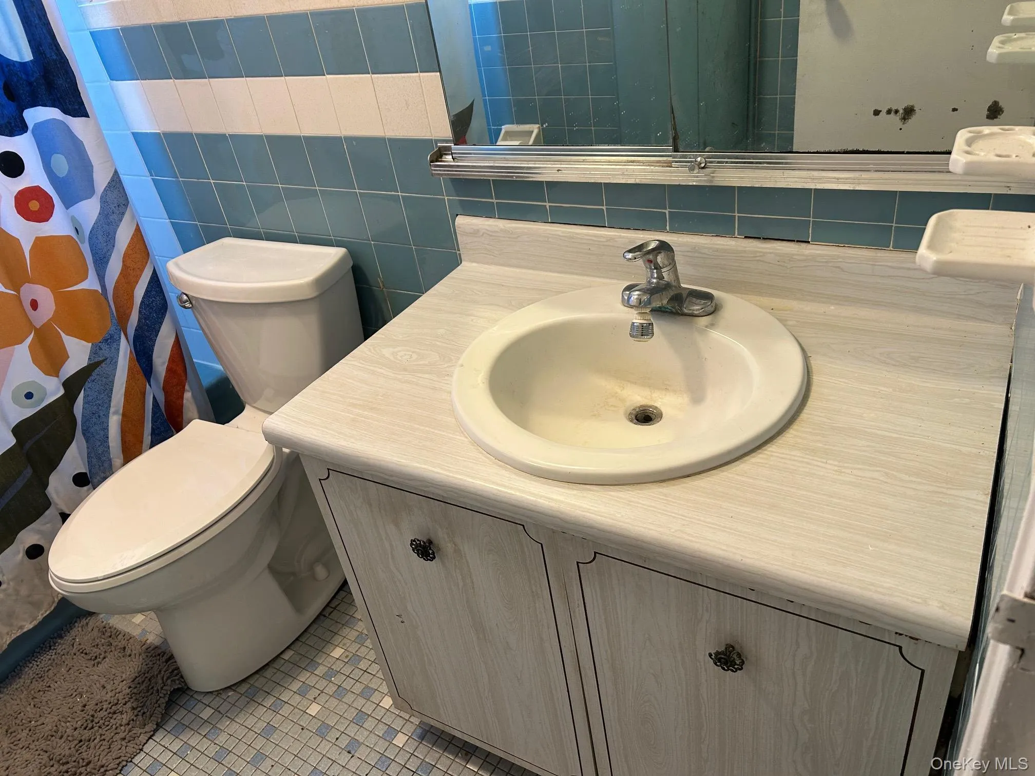 Full bathroom with vanity, curtained shower, light tile patterned flooring, and tile walls Full bathroom with vanity, curtained shower, light tile patterned flooring, and tile walls