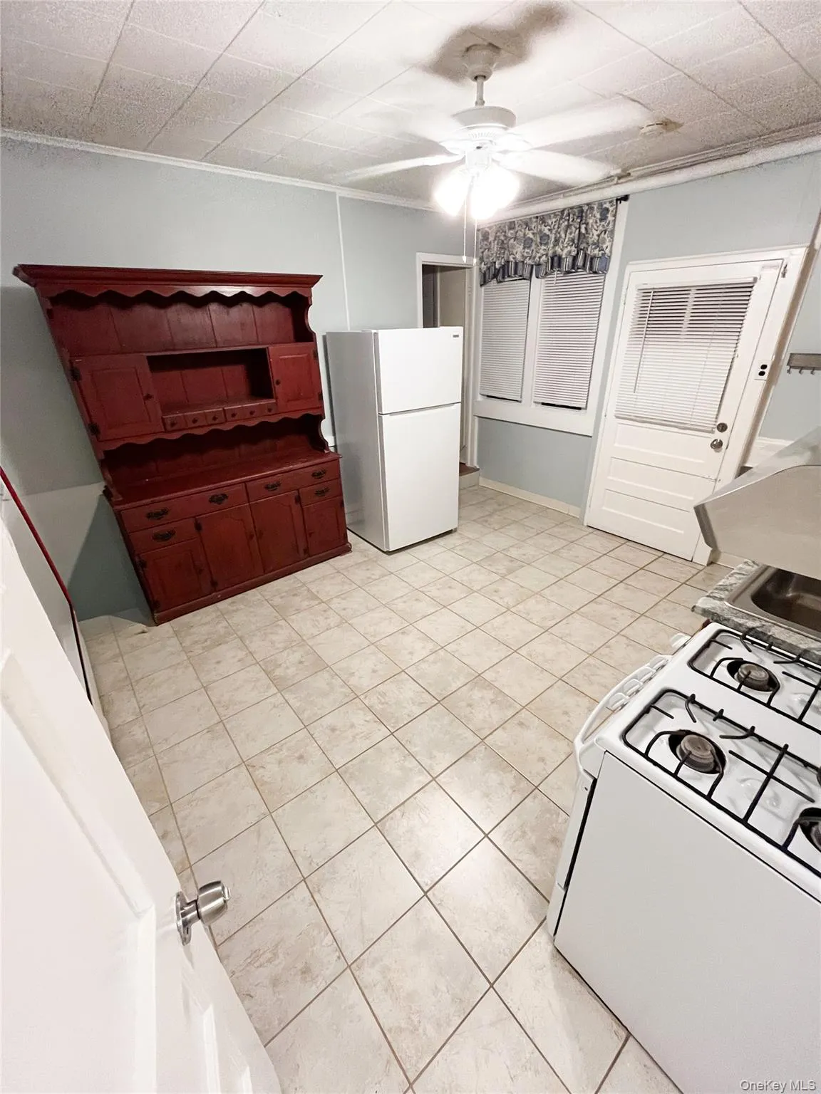 Kitchen featuring white appliances, crown molding, ceiling fan, and light tile patterned floors Kitchen featuring white appliances, crown molding, ceiling fan, and light tile patterned floors