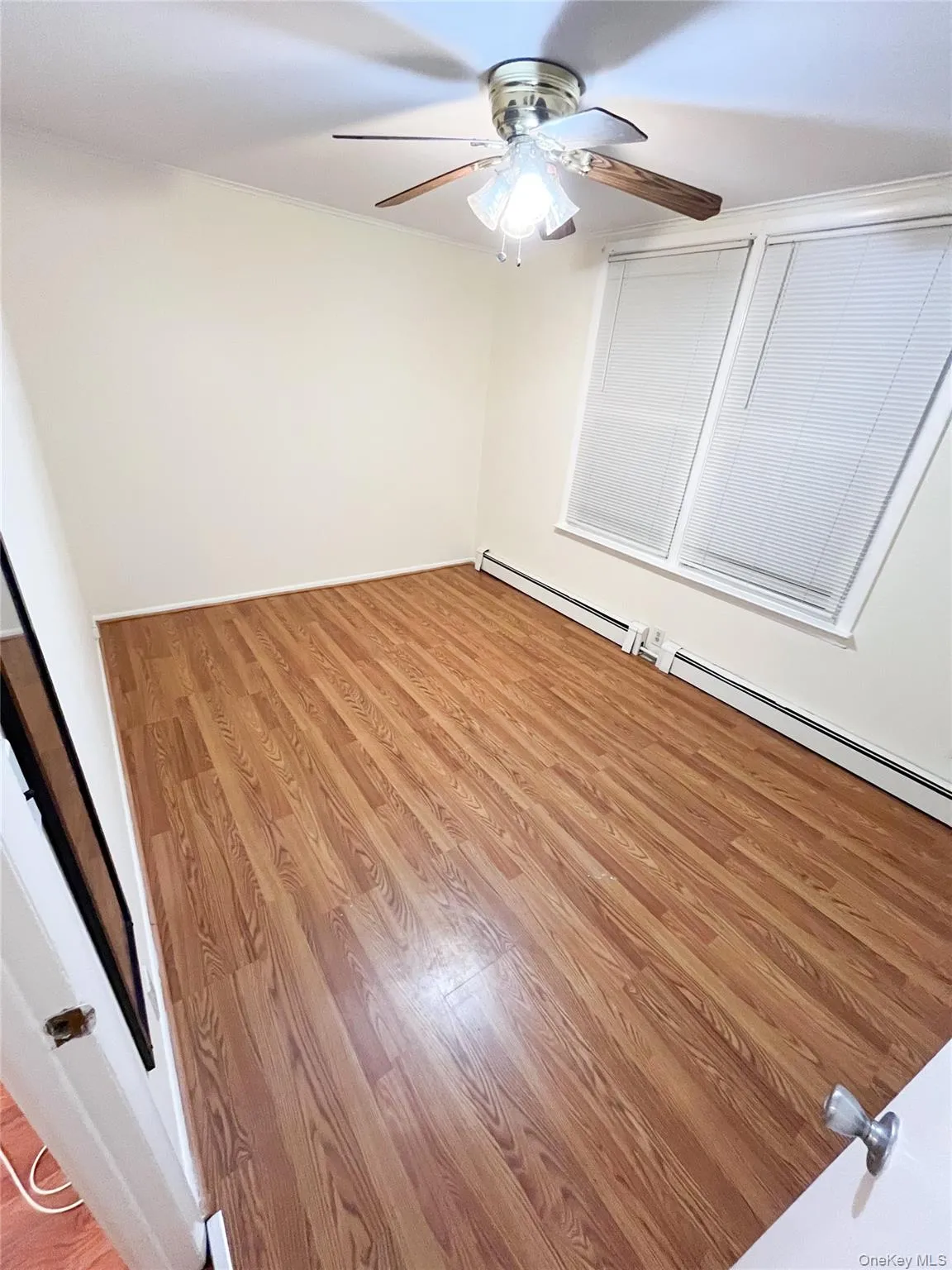 Empty room featuring light wood-style floors, a baseboard heating unit, ceiling fan, and crown molding Empty room featuring light wood-style floors, a baseboard heating unit, ceiling fan, and crown molding