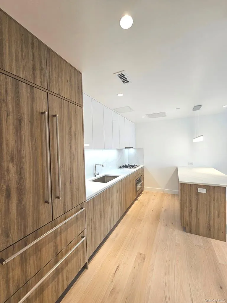 Kitchen featuring brown cabinetry, modern cabinets, decorative light fixtures, and recessed lighting Kitchen featuring brown cabinetry, modern cabinets, decorative light fixtures, and recessed lighting